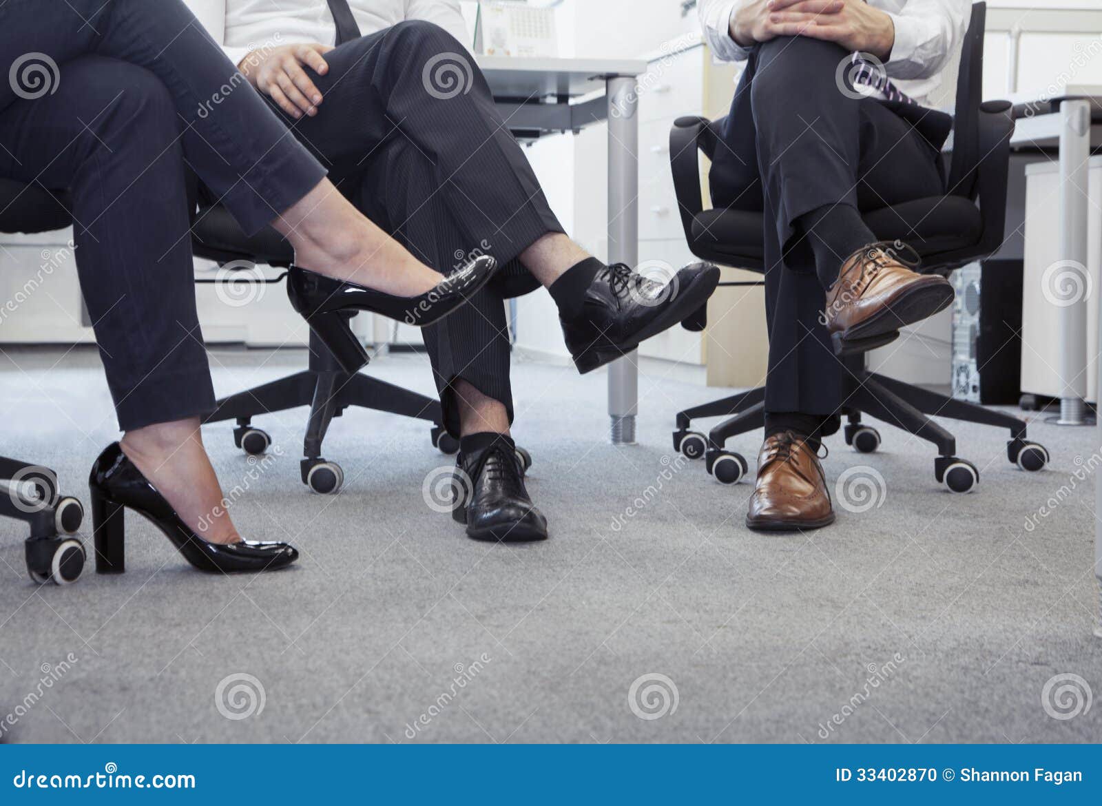 Three Business People with Legs Crossed Sitting on Chairs, Low Section