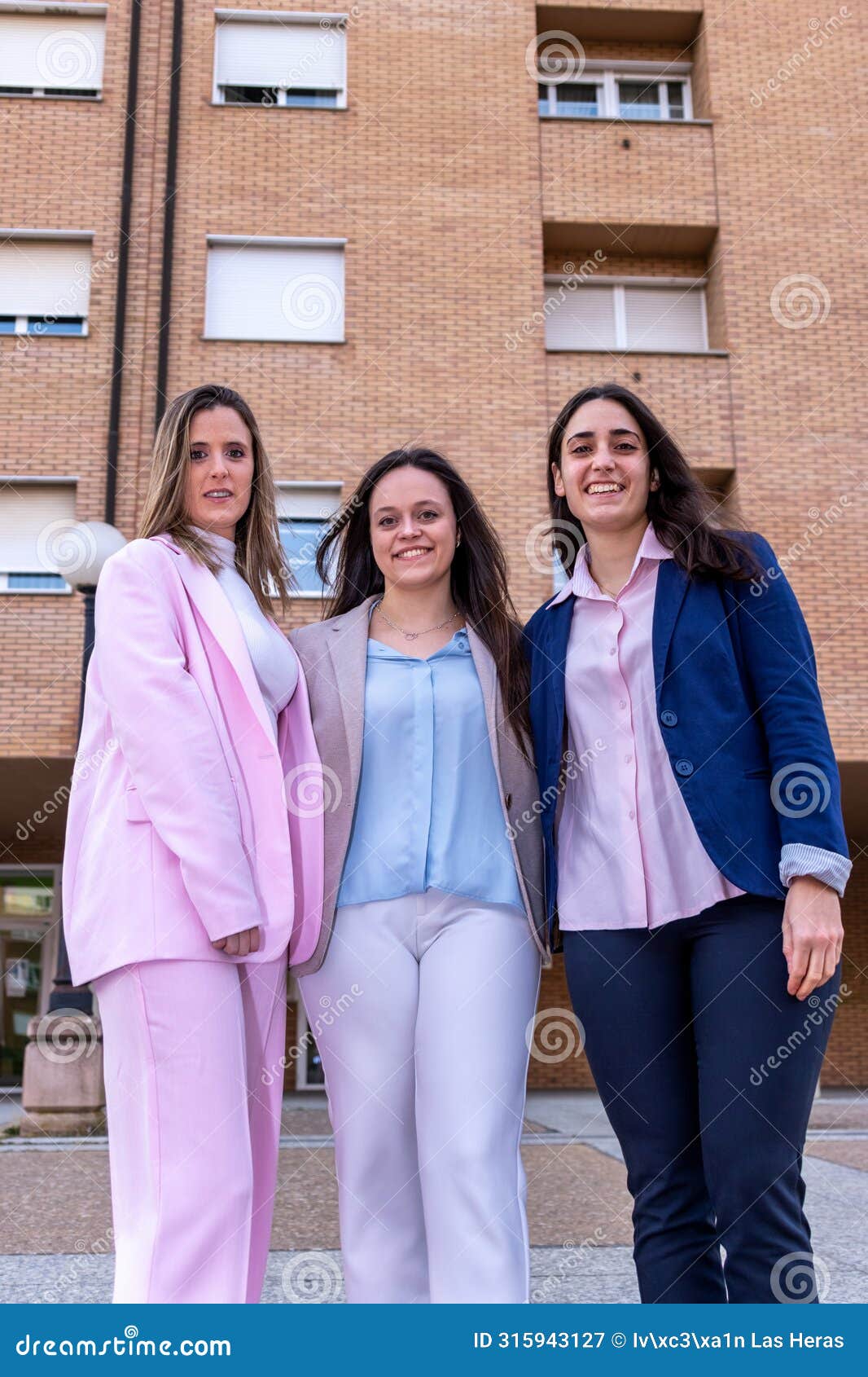 three business women are standing in front of a buildin