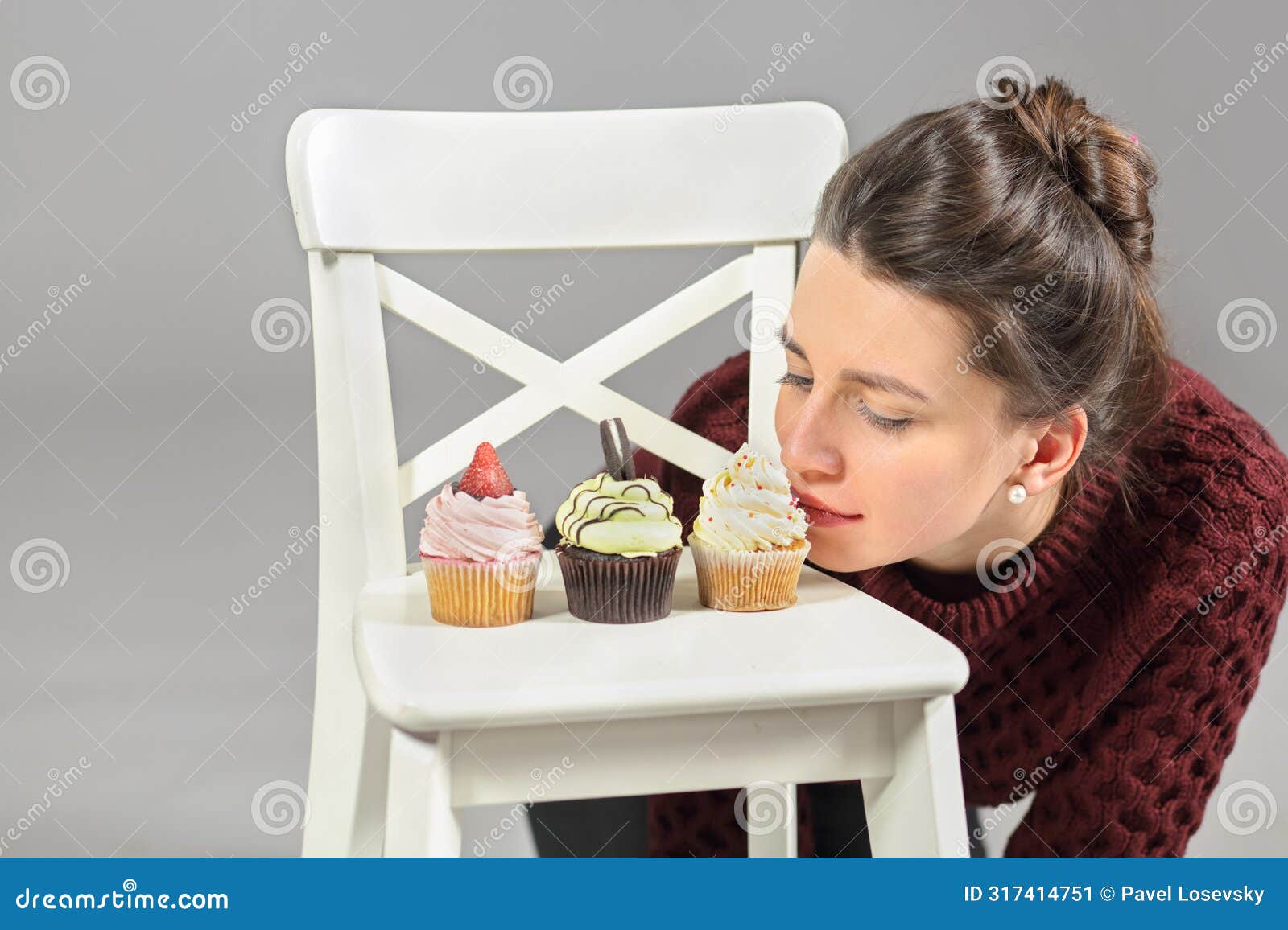 three cakes stand on white chair, young girl bent