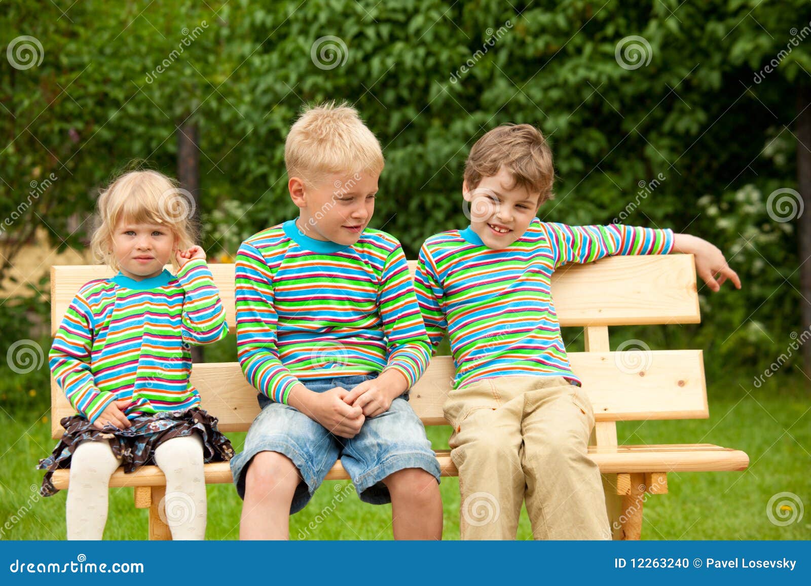 three children on a bench in identical clothes