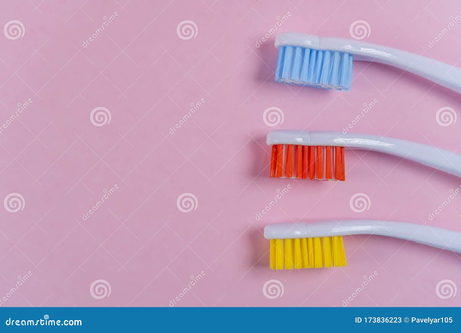 Three Colored Toothbrushes on a Pink Background. Red, Yellow, Blue ...