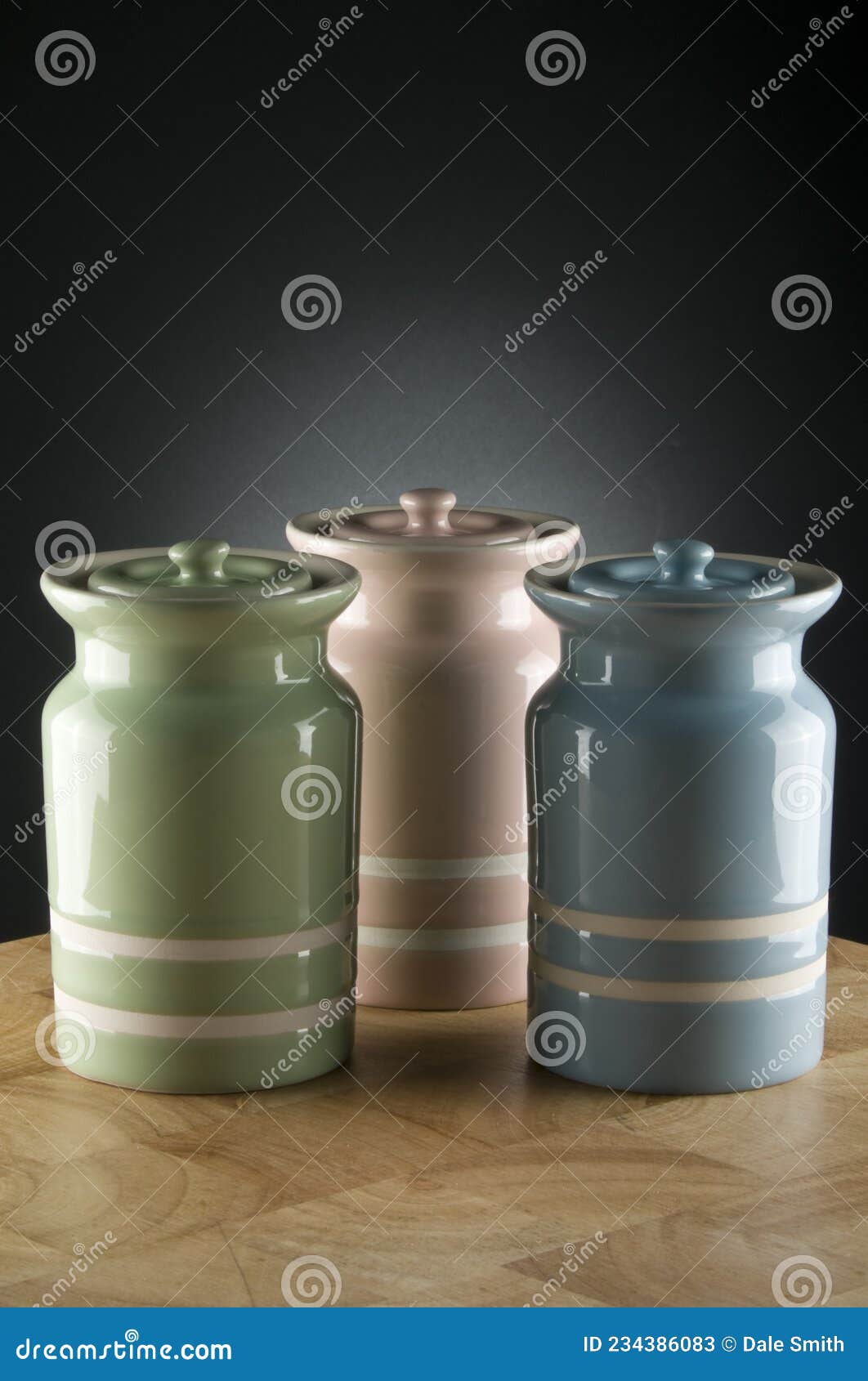 Three Colourful Ceramic Canisters on Timber Bench with Grey Spot on