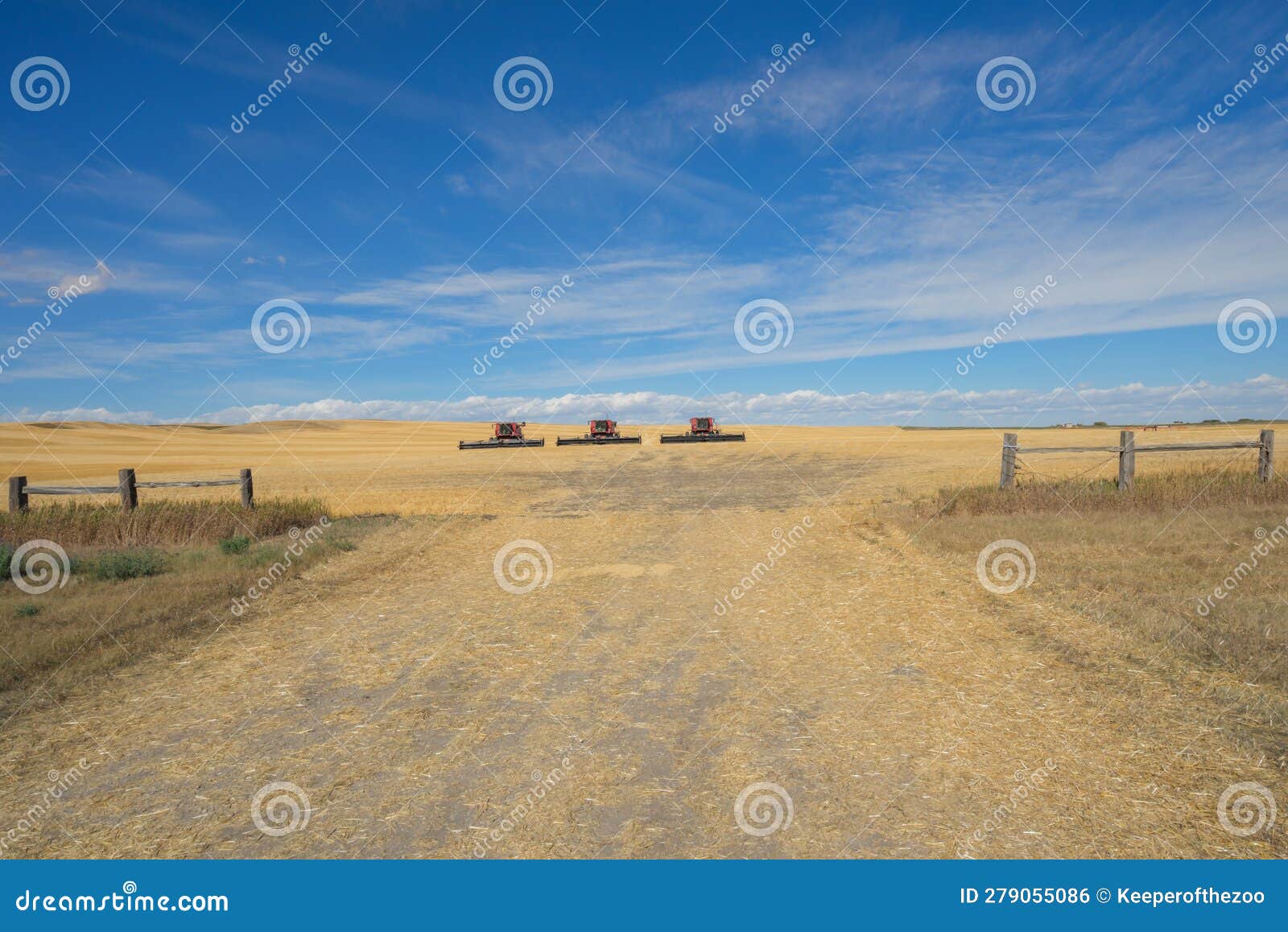 Three Combine Harvester Sitting in a Field with a Cloudy Blue Sky Stock