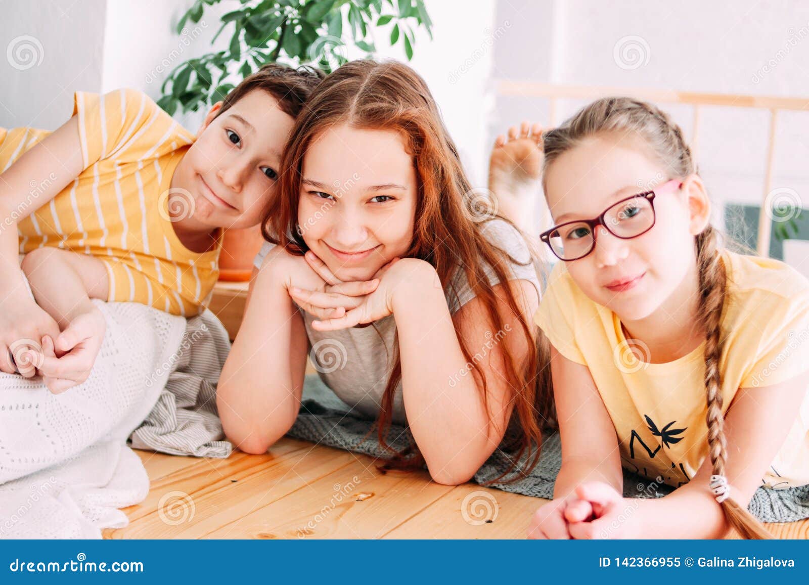 three cute smiling children friends tweens lying on the floor