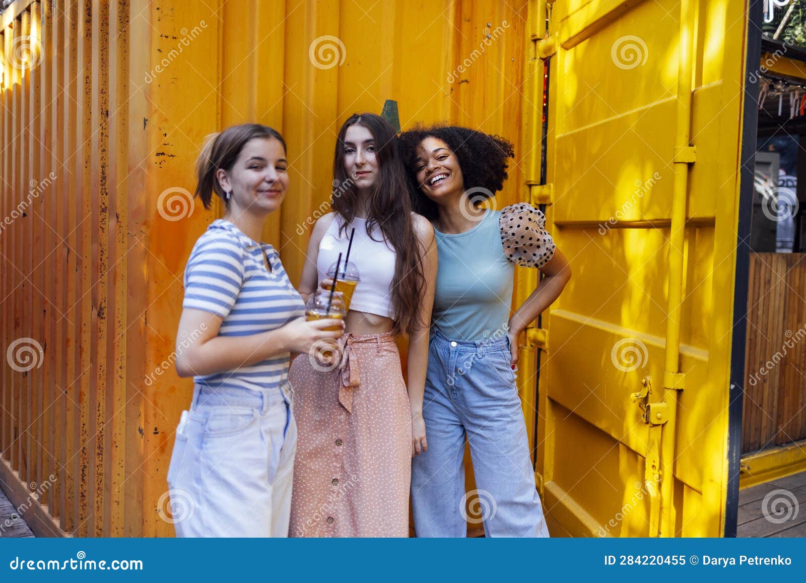 Three Funny Street Style Hipster Girls Posing At White Brick Wall