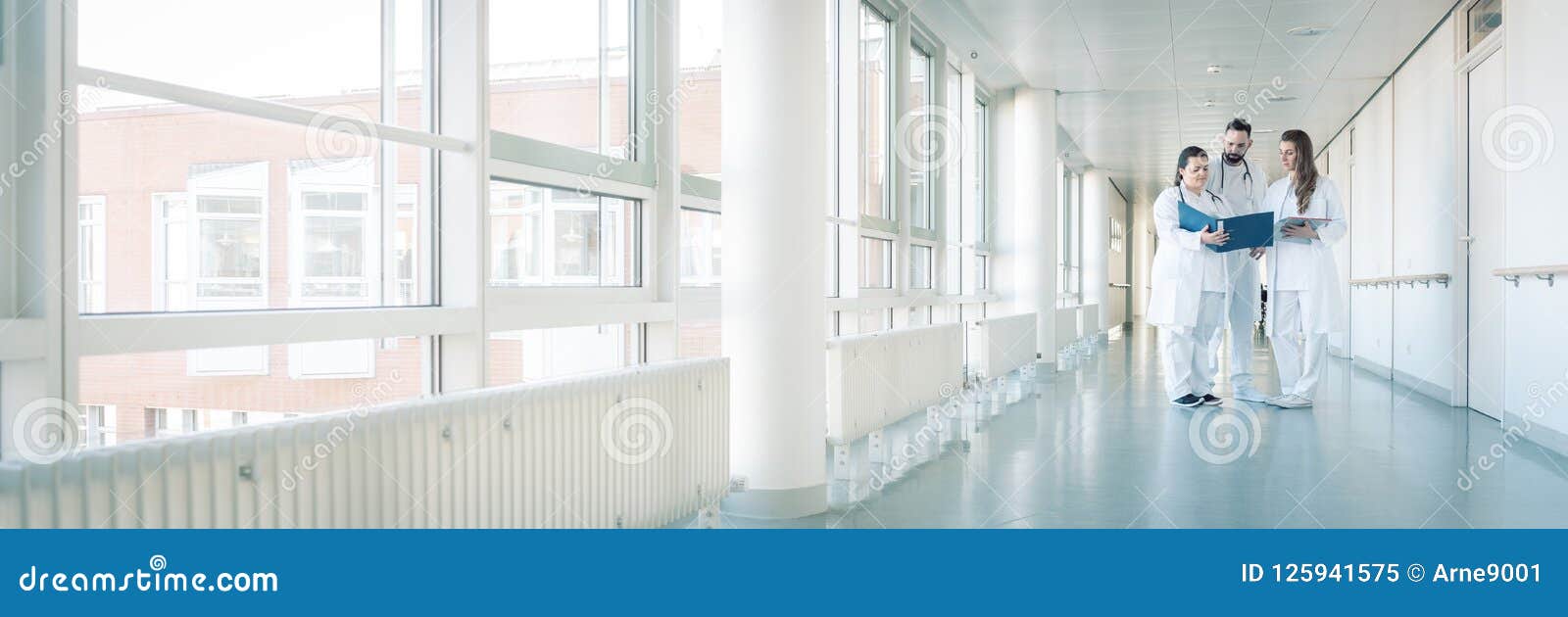 three doctors on hospital corridor having short meeting