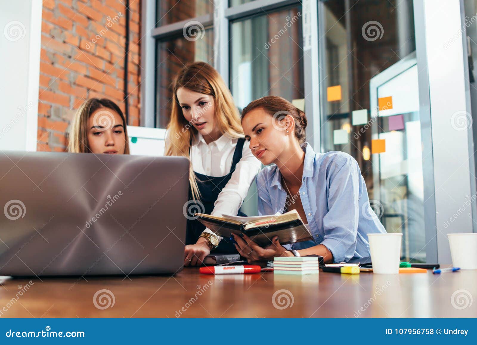Three Female College Students Doing Homework Together Using One