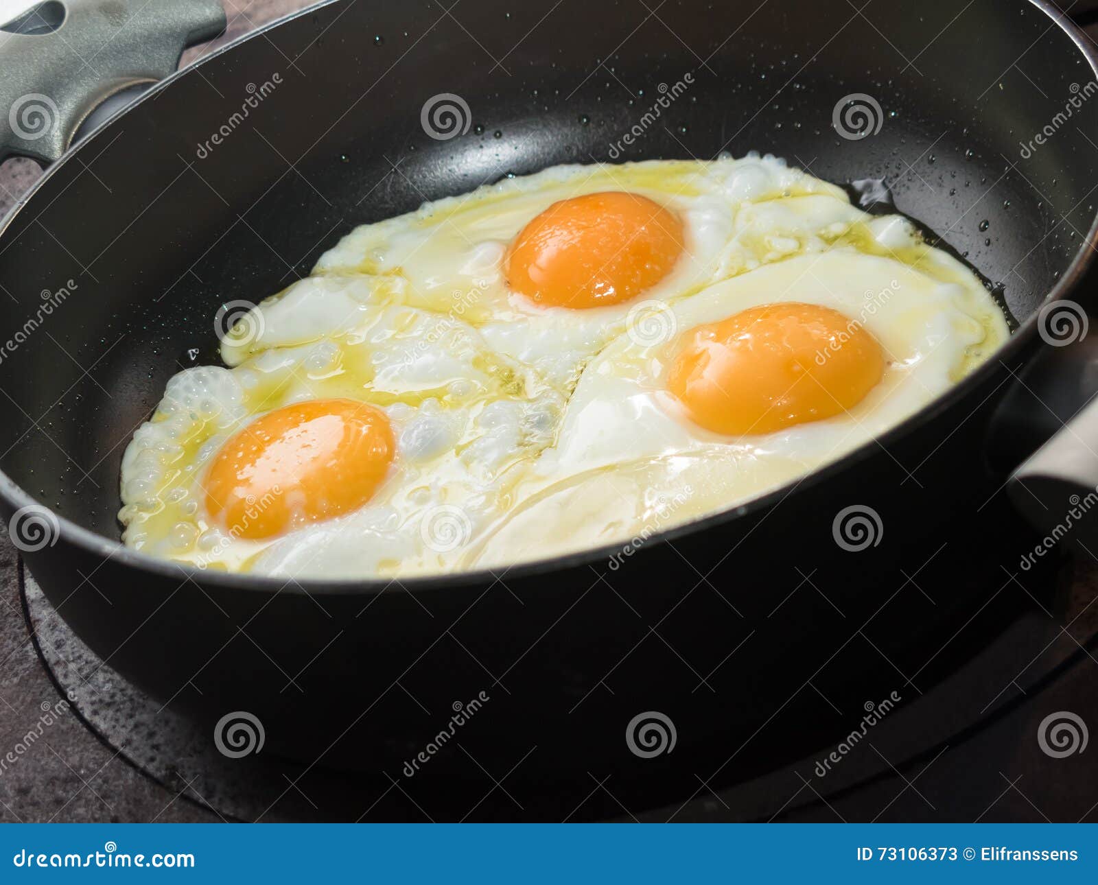 Three Fried Eggs In Cast Iron Frying Pan Isolated On White Paint Stock