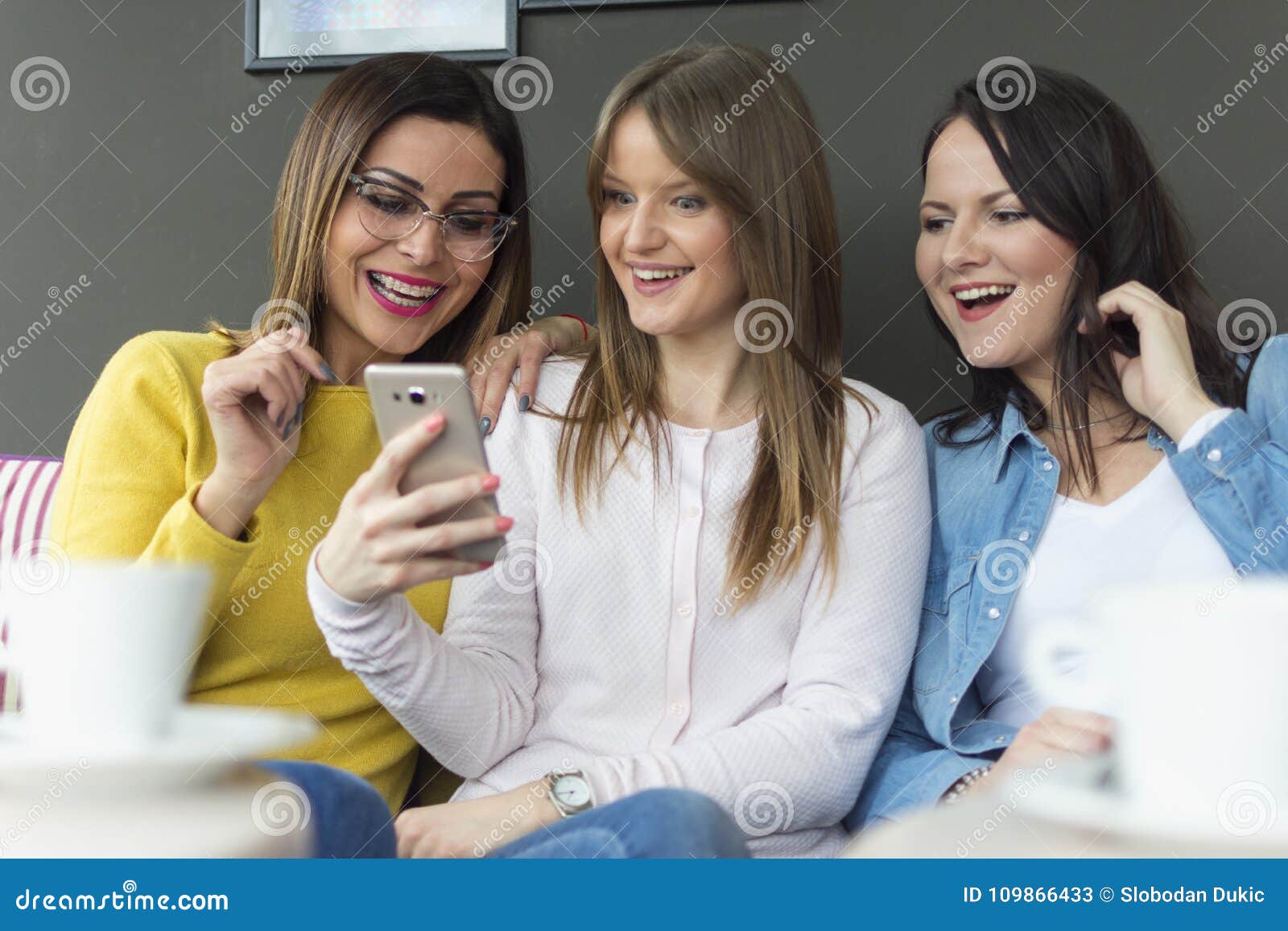 Three Friends Sit and Use a Mobile Phone Stock Image - Image of ...