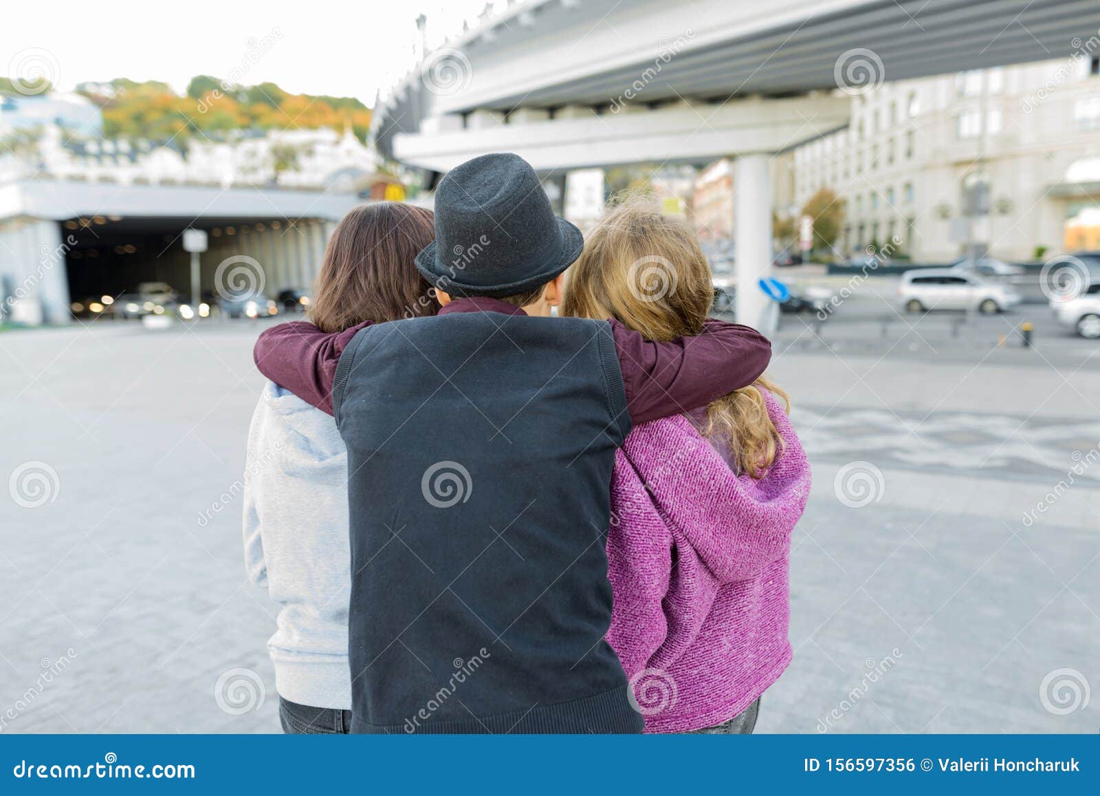 Three Friends View From The Back Of Boy Hugging Two Girls Stock Photo