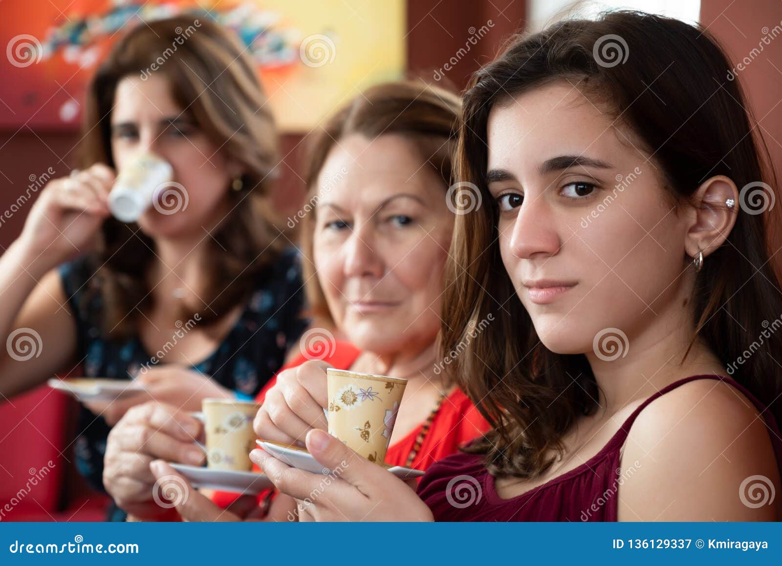 three generations of hispanic women drinking coffee