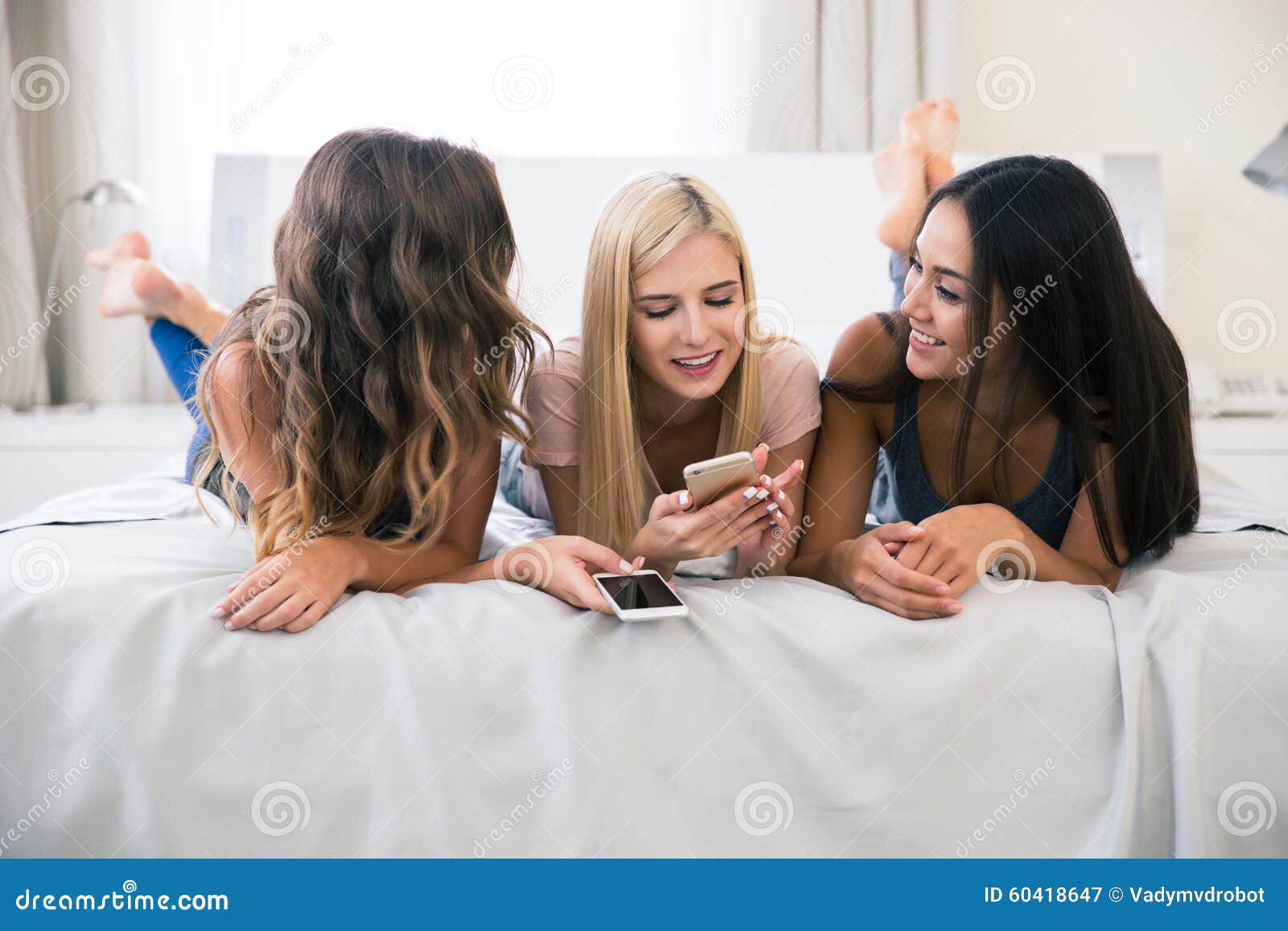 Three Girlfriends Lying on the Bed with Smartphone Stock Image - Image ...