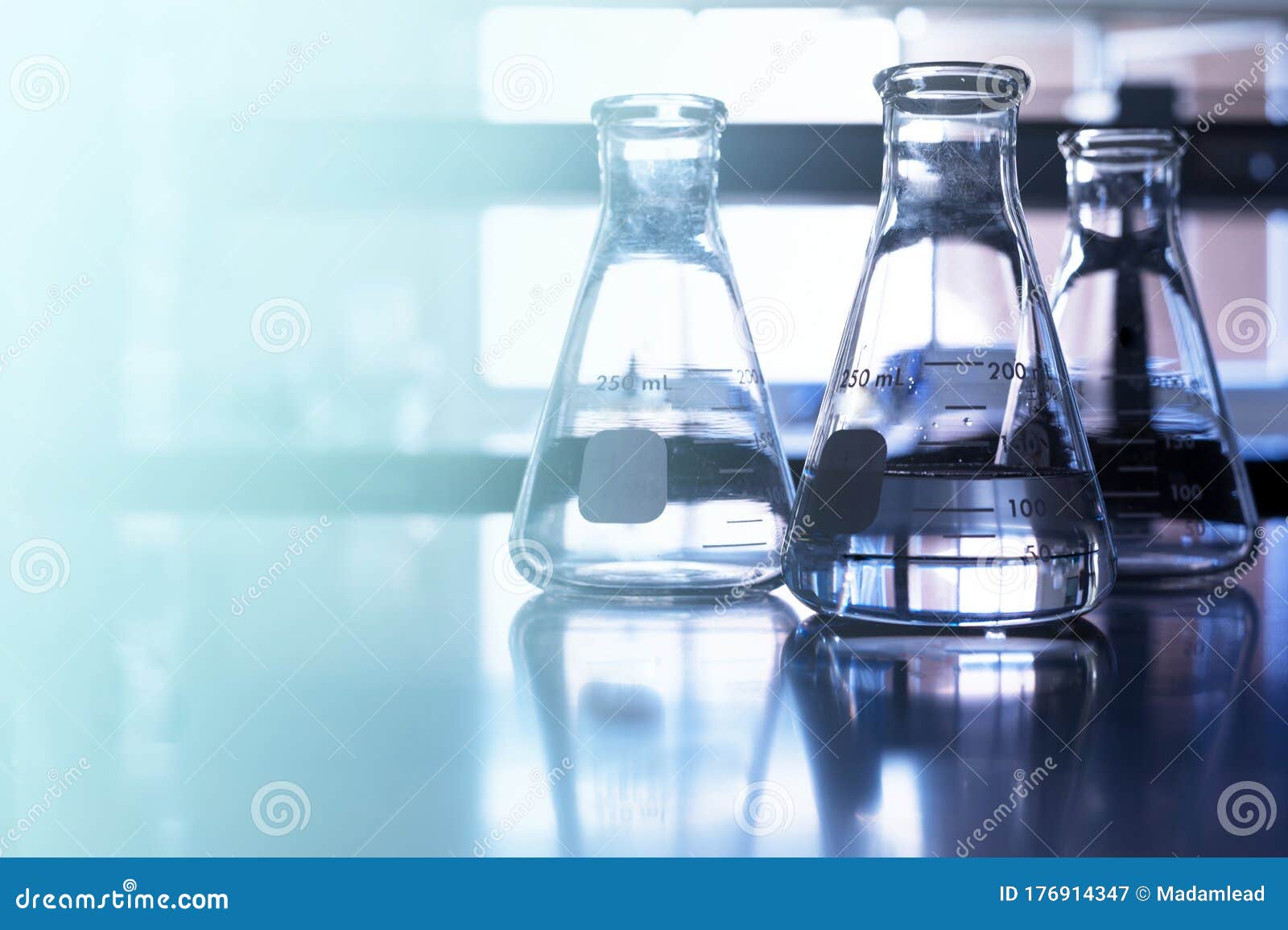 На столе стоят три склянки с водой. AG Chemistry. Perfect Testing Laboratoria background image.
