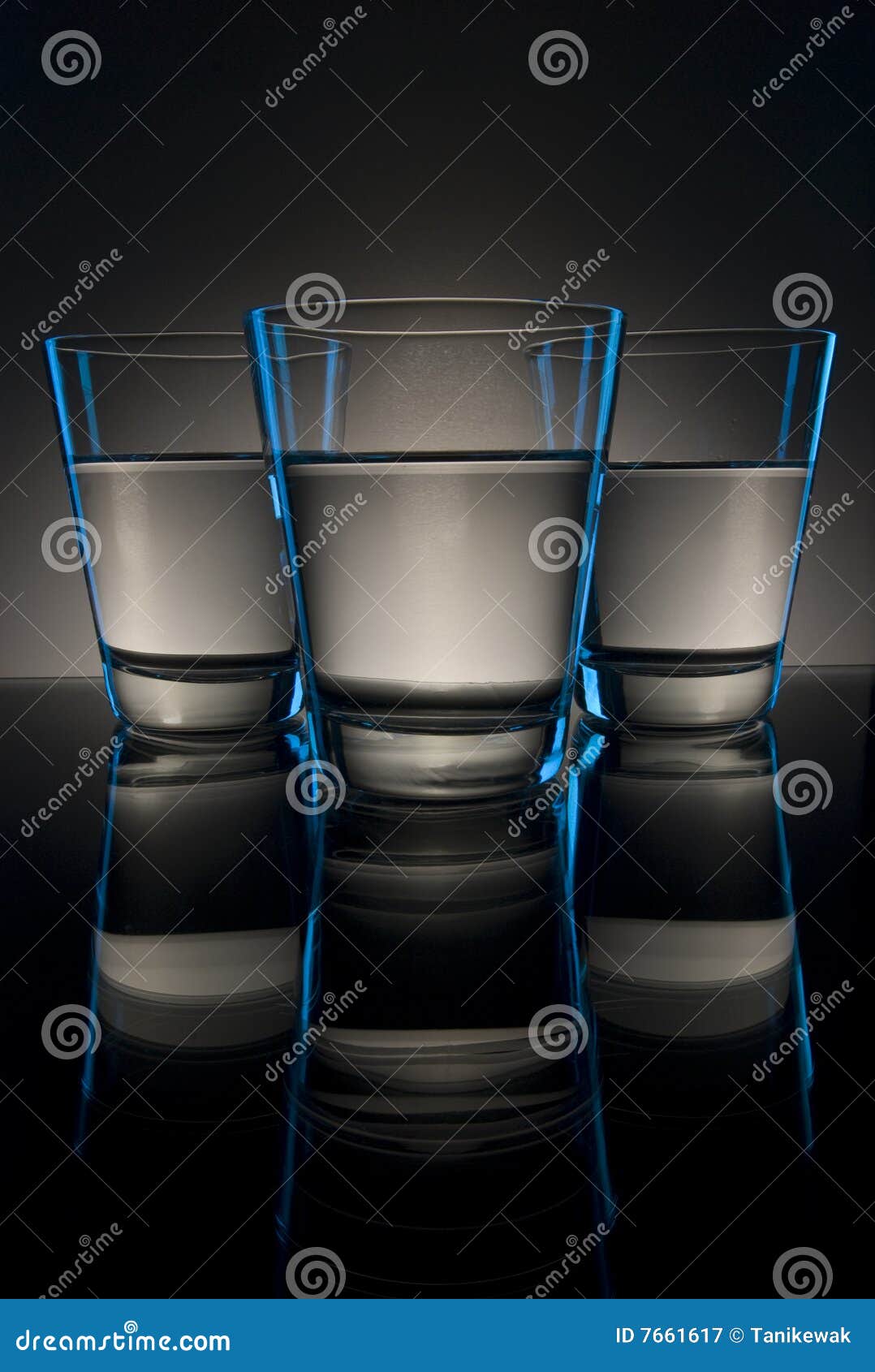 View of three glasses containing alcohol on a reflective surface.