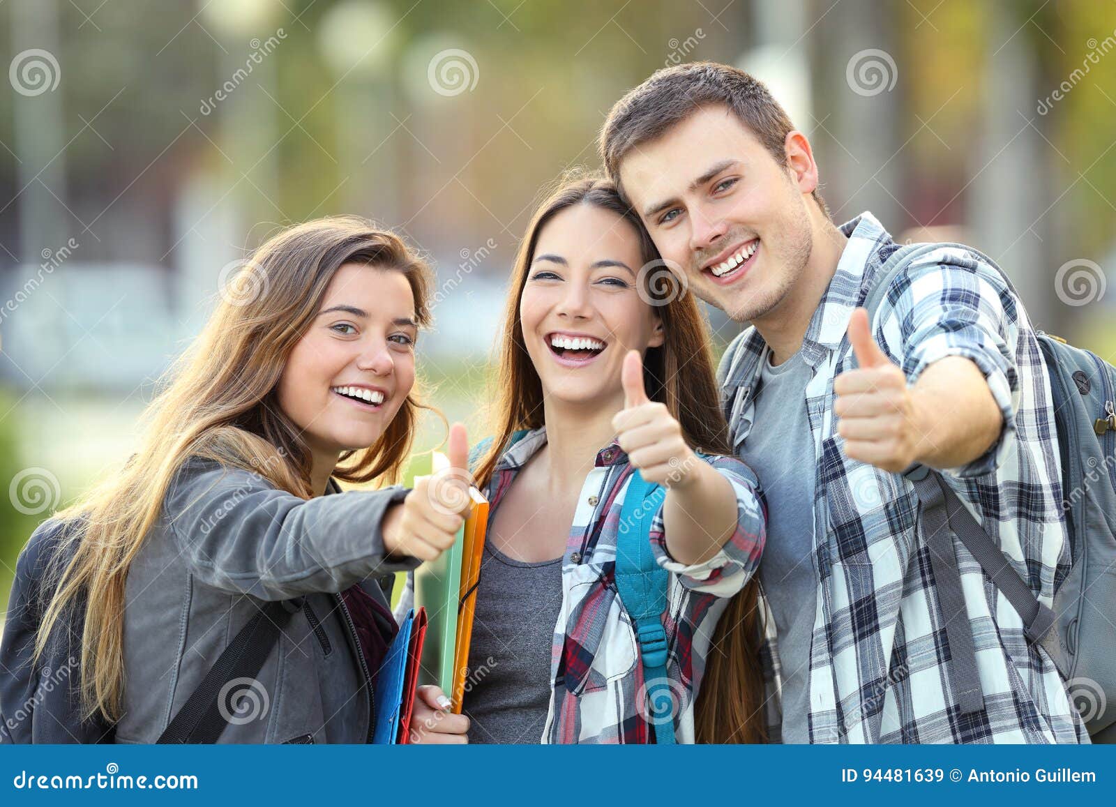 three happy students with thumbs up
