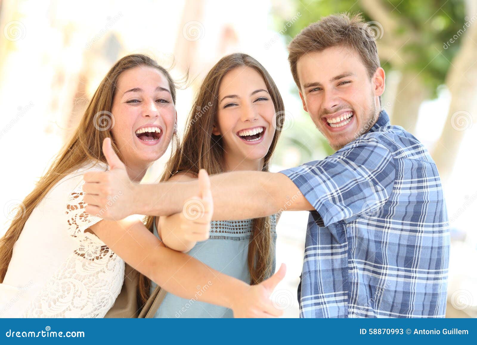 three happy teenagers laughing with thumbs up