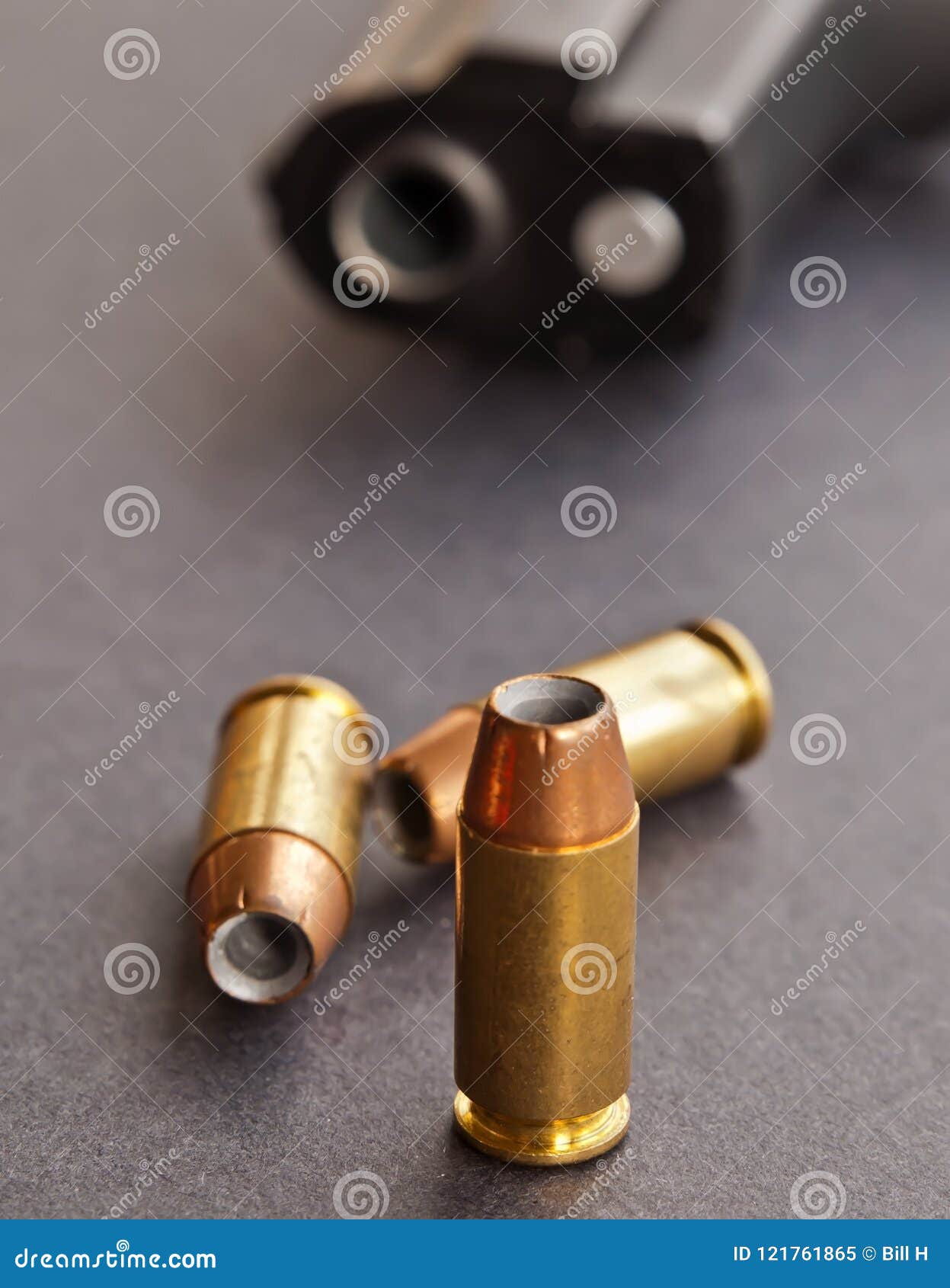 three hollow point bullets in front of a black pistol