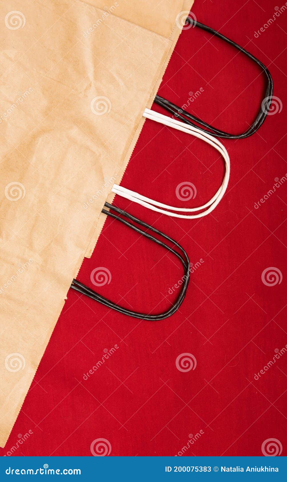 Three Kraft Paper Recyclable Bags with Handles Lie on a Red Background