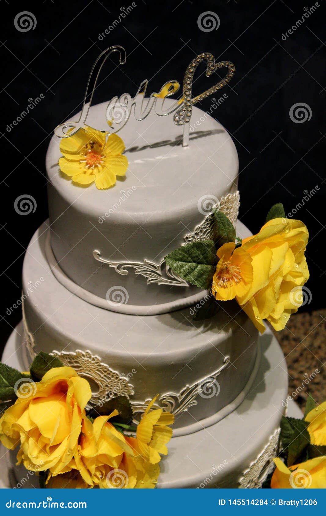 Three Layer Wedding Cake with Yellow Flowers and the Word Love ...