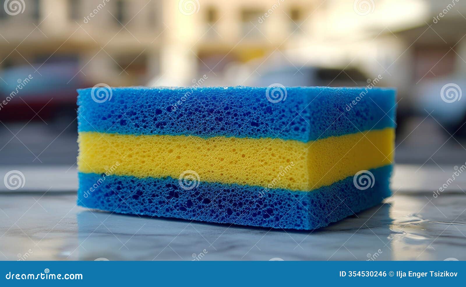 three-layered cleaning sponge in blue and yellow on reflective surface, ideal for text placement