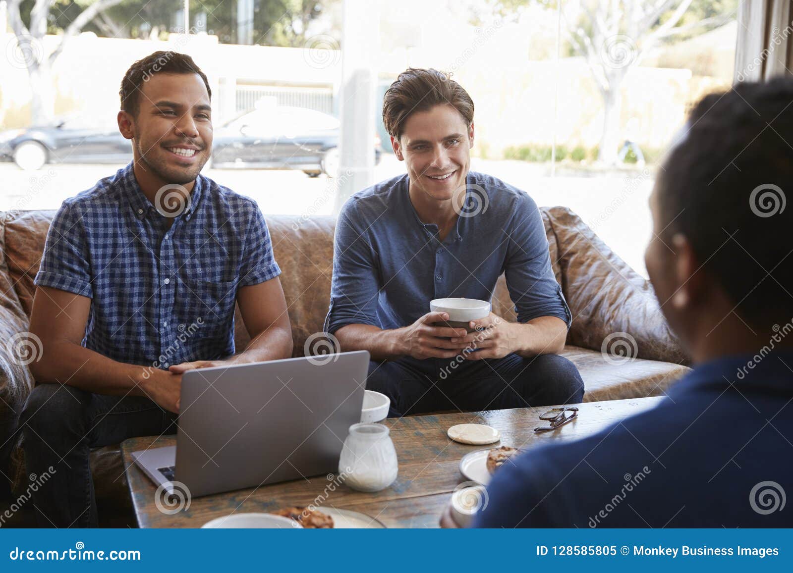 Three Male Friends Talking Over Coffee at a Coffee Shop Stock Image