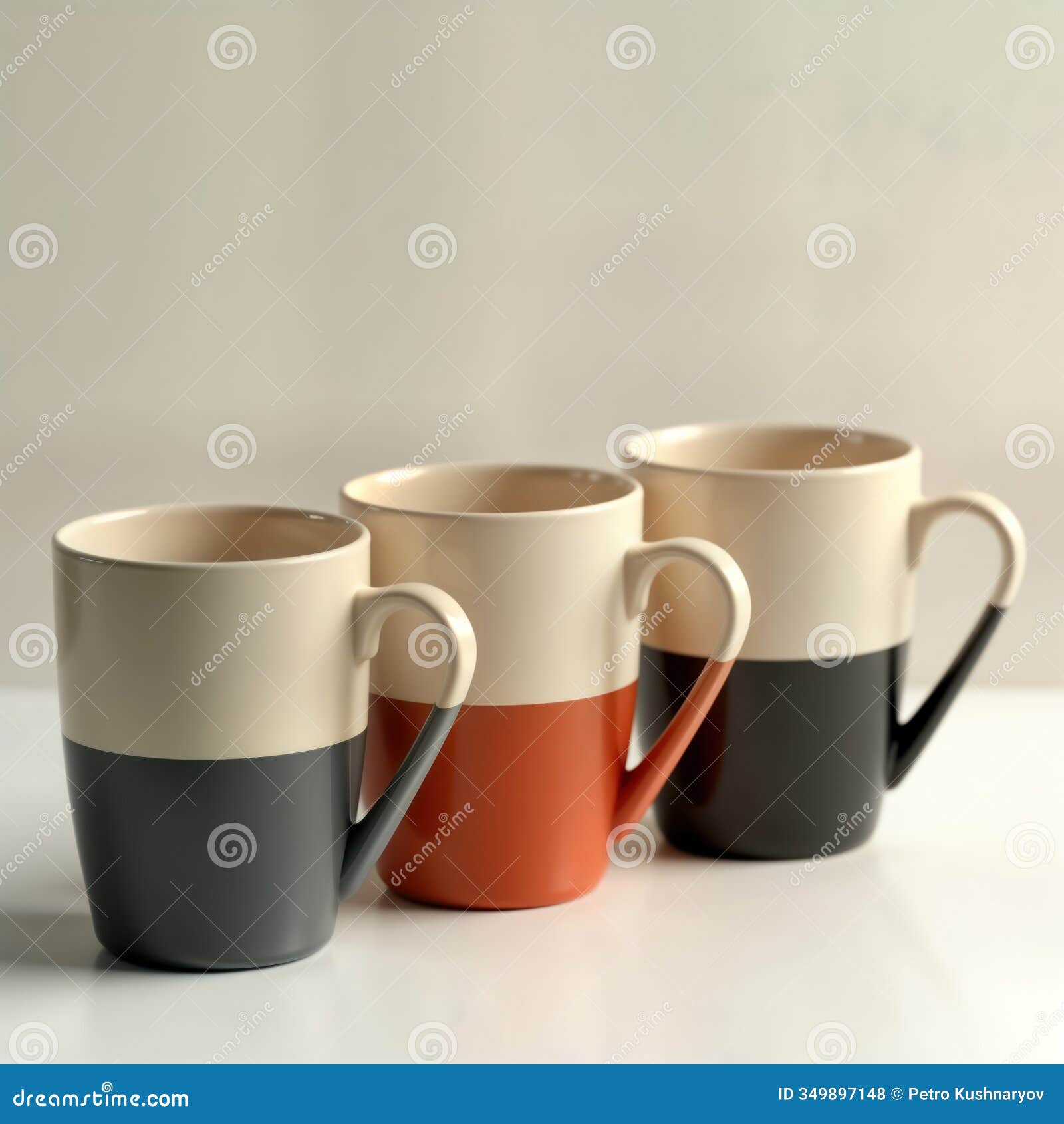 three modern coffee mugs stand on white surface. mugs color gradients. one grey, cream, another orange, cream, third black,