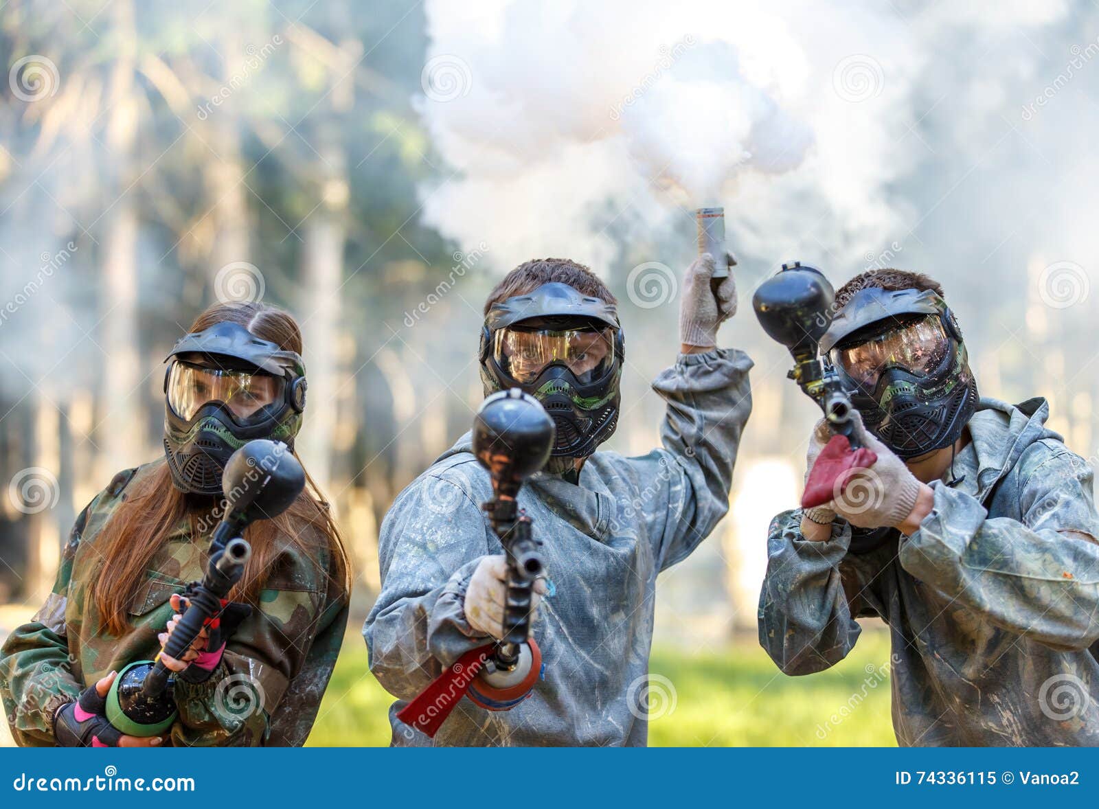 Three Paintball Players with Guns and Smoke Grenade Aiming Stock Image