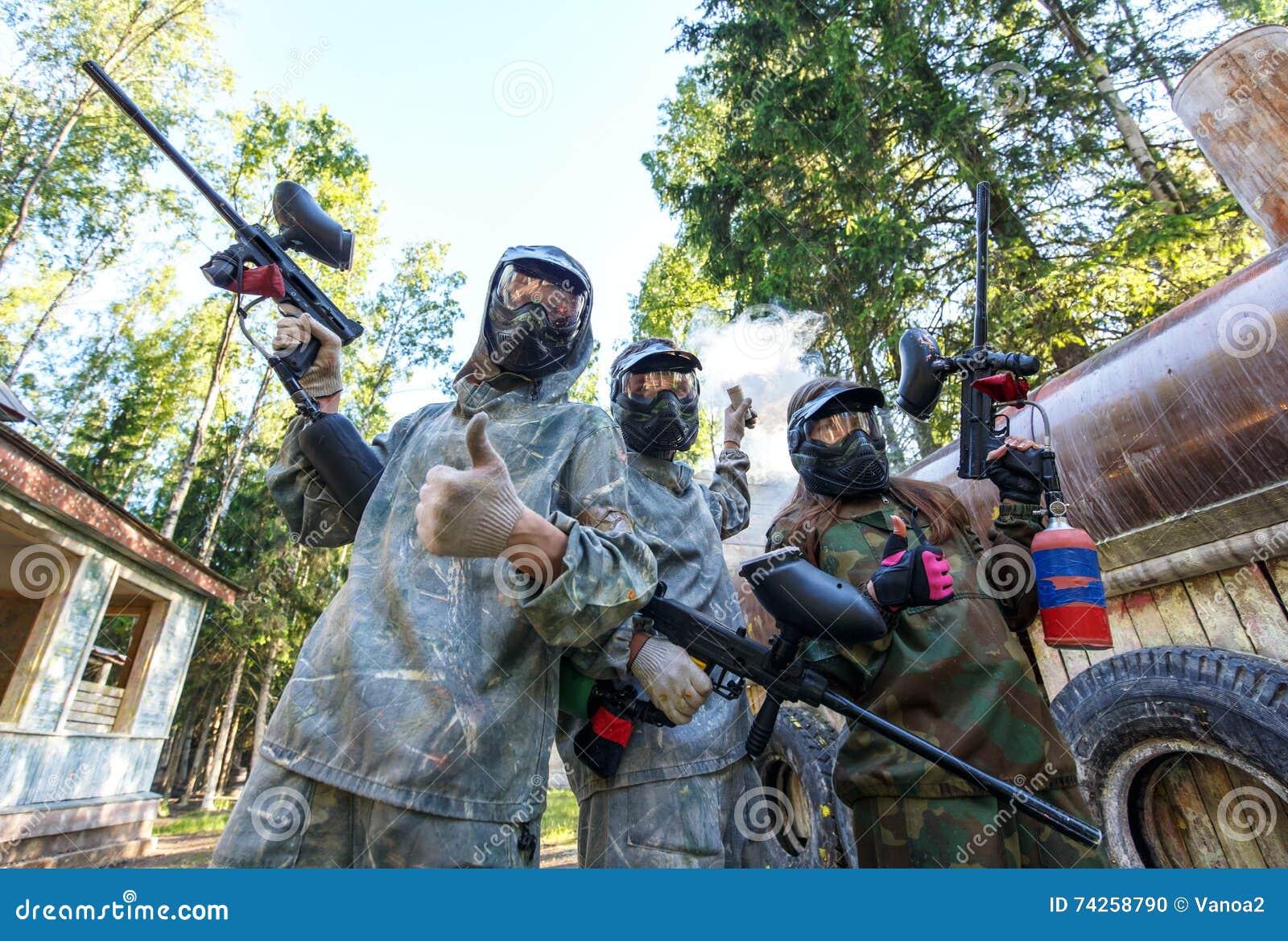 Three Paintball Players with Smoke Grenade Posing in Masks Stock Photo