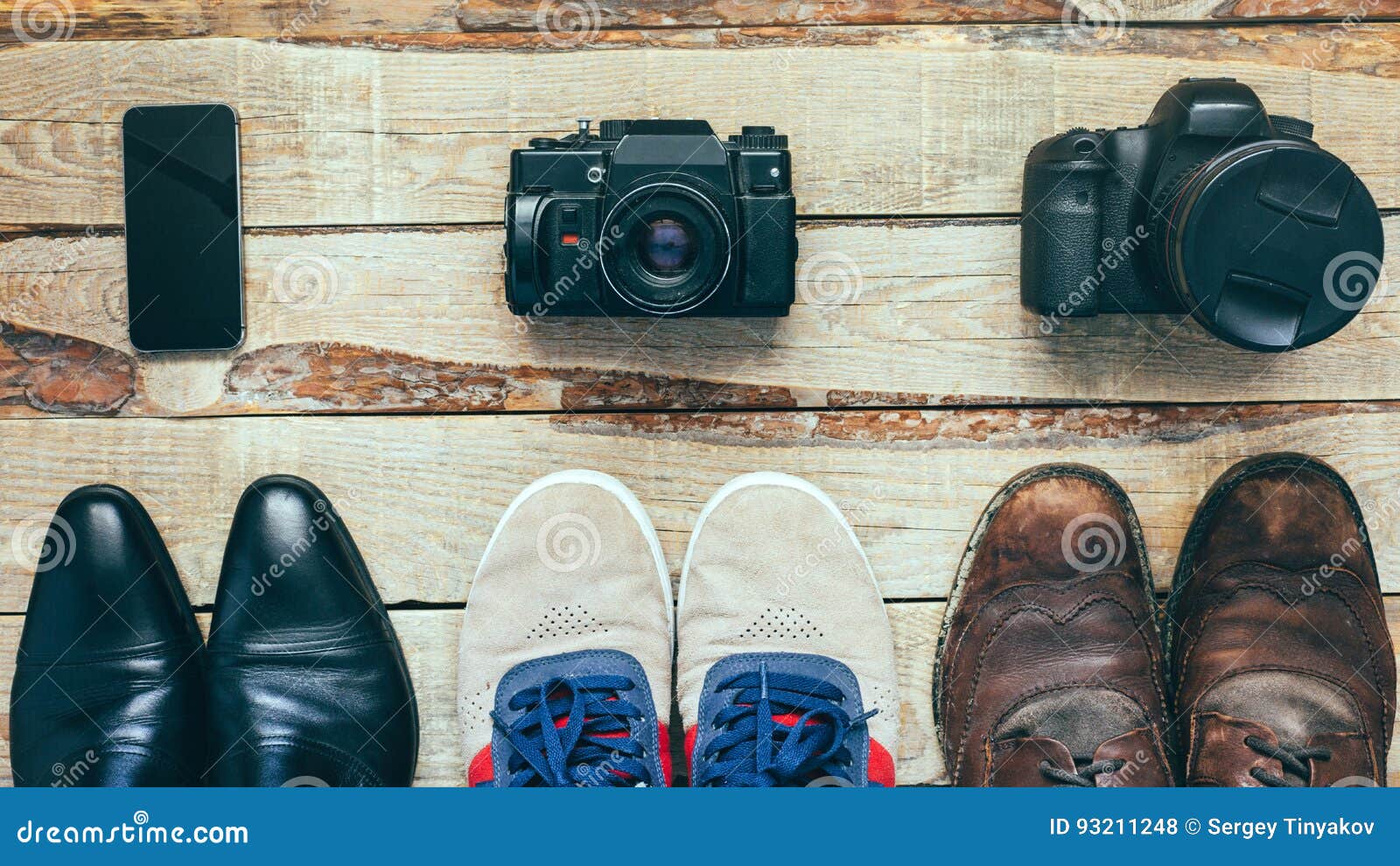 three pairs of shoes and three cameras. busines shoes, casual shoes, hiking boots on wooden backgriound concept of choosing right