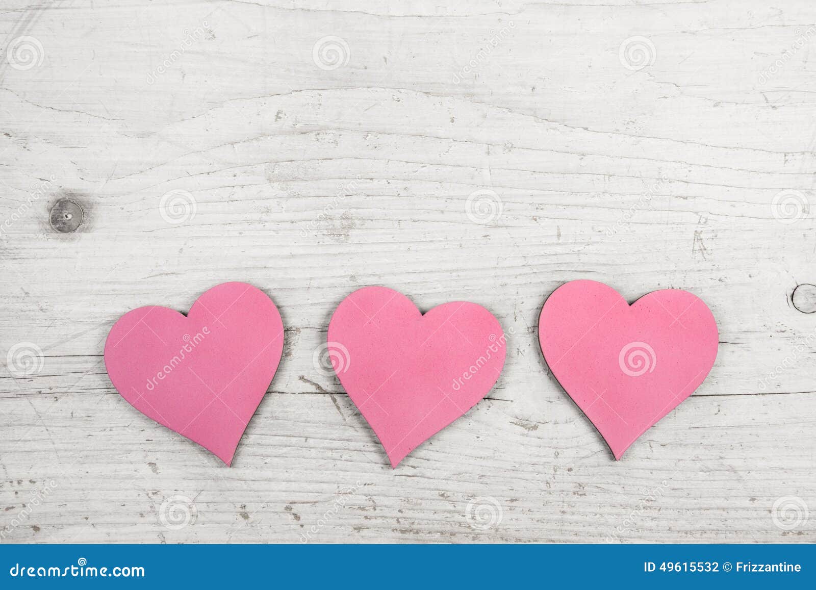 Three pink hearts on old wooden white shabby chic background.