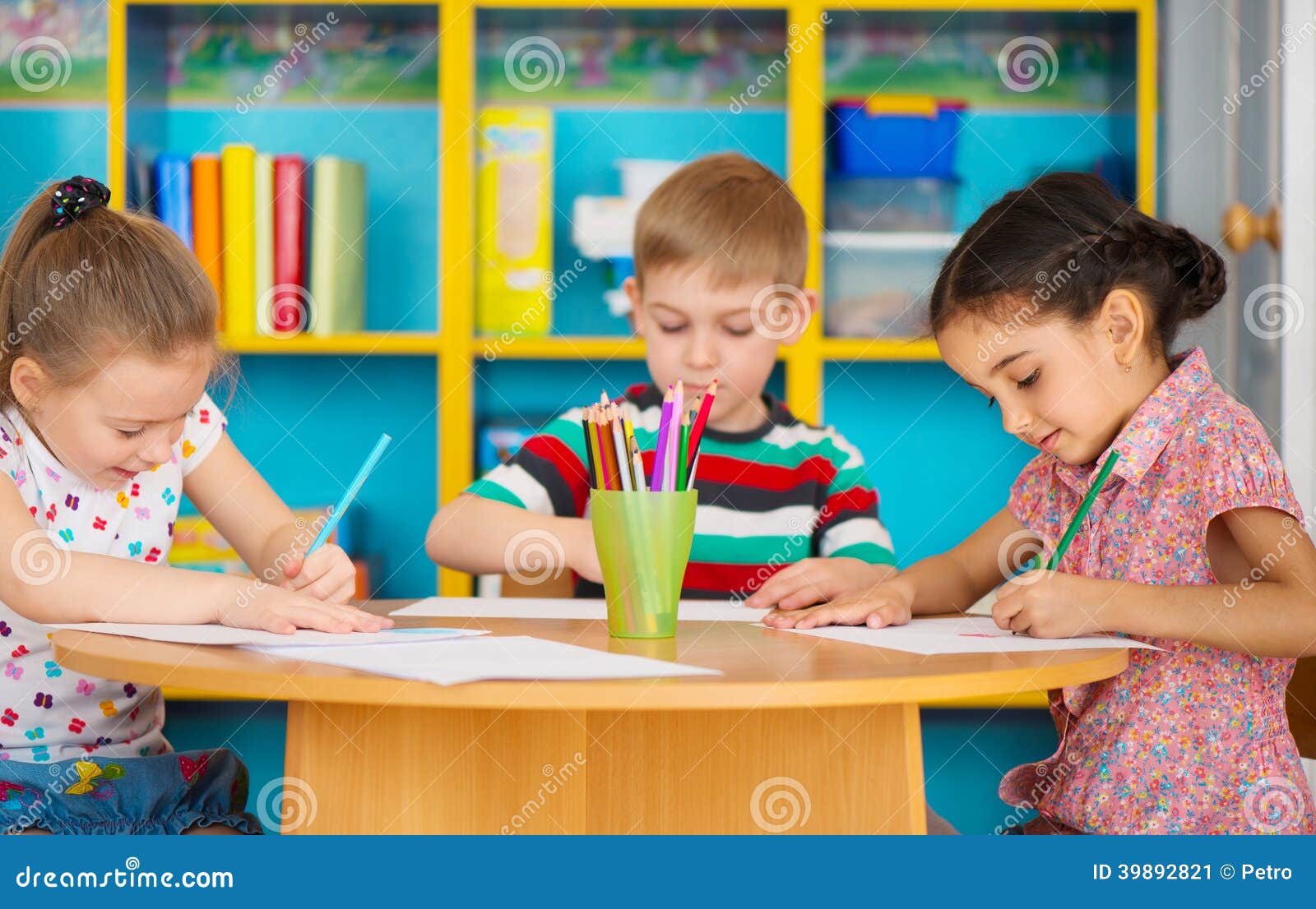 three preschool children drawing at daycare