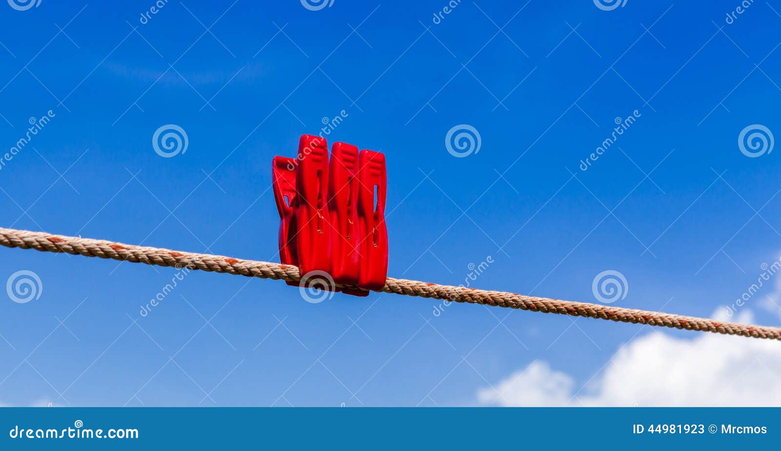 Three Red Plastic Clothespins are on Clothesline with Blurry Blu Stock