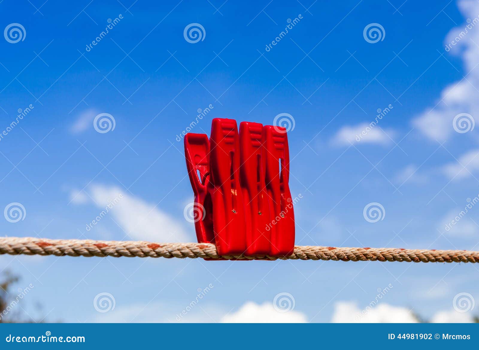 Three Red Plastic Clothespins Hang on a Laundry Line. Stock Photo