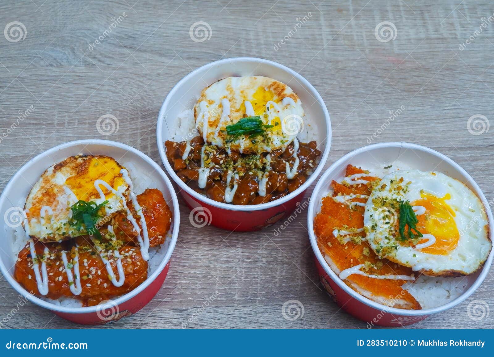 Three Rice Bowls Containing Rice, Chicken and Egg with Spicy Tomato