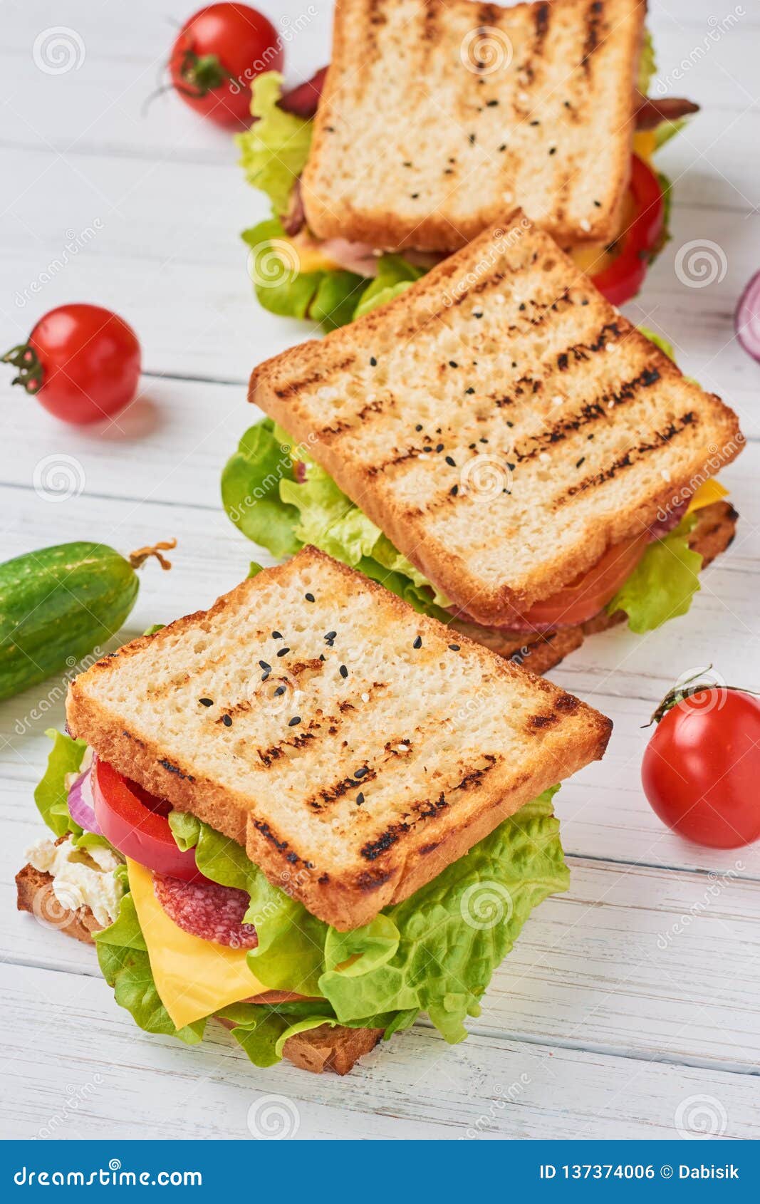 Three Sandwiches with Ham, Lettuce and Fresh Vegetables on a White