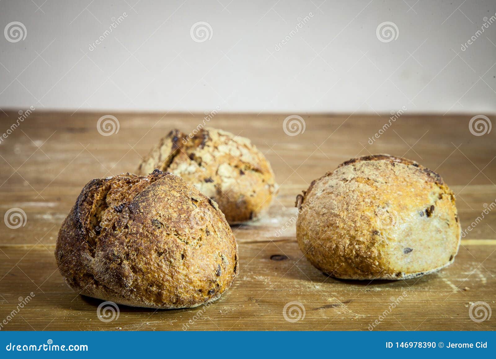 Three Small Loafs Of French Bread On Display On A Rustic Wooden