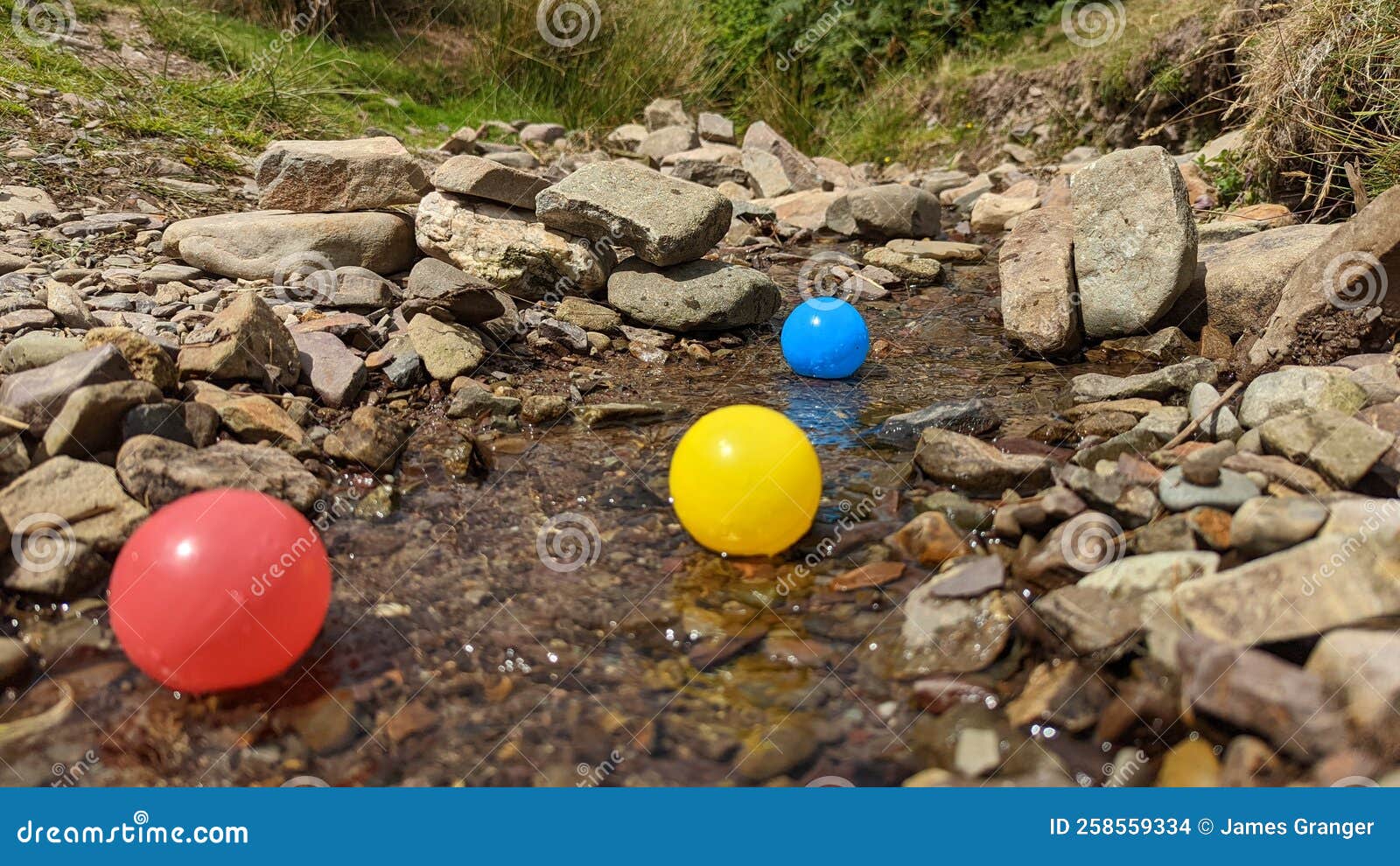 Three Small Primary Colored Plastic Balls Drifting Down the Stream