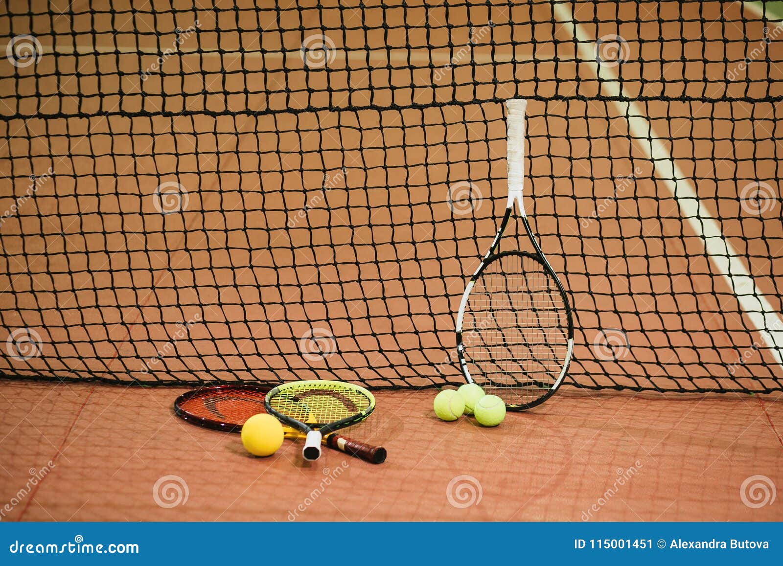 three tennis rackets and balls on the indoor court