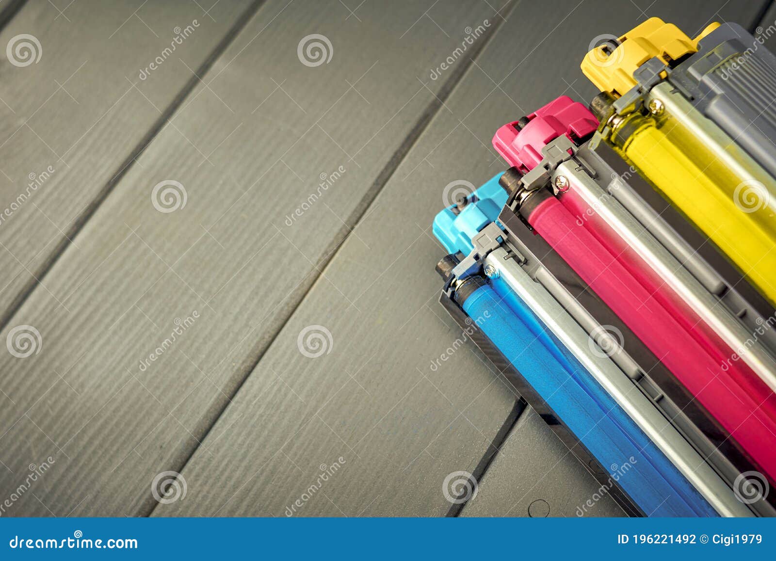 three used toner cartridges in a color laser printer on gray wooden background for recycling
