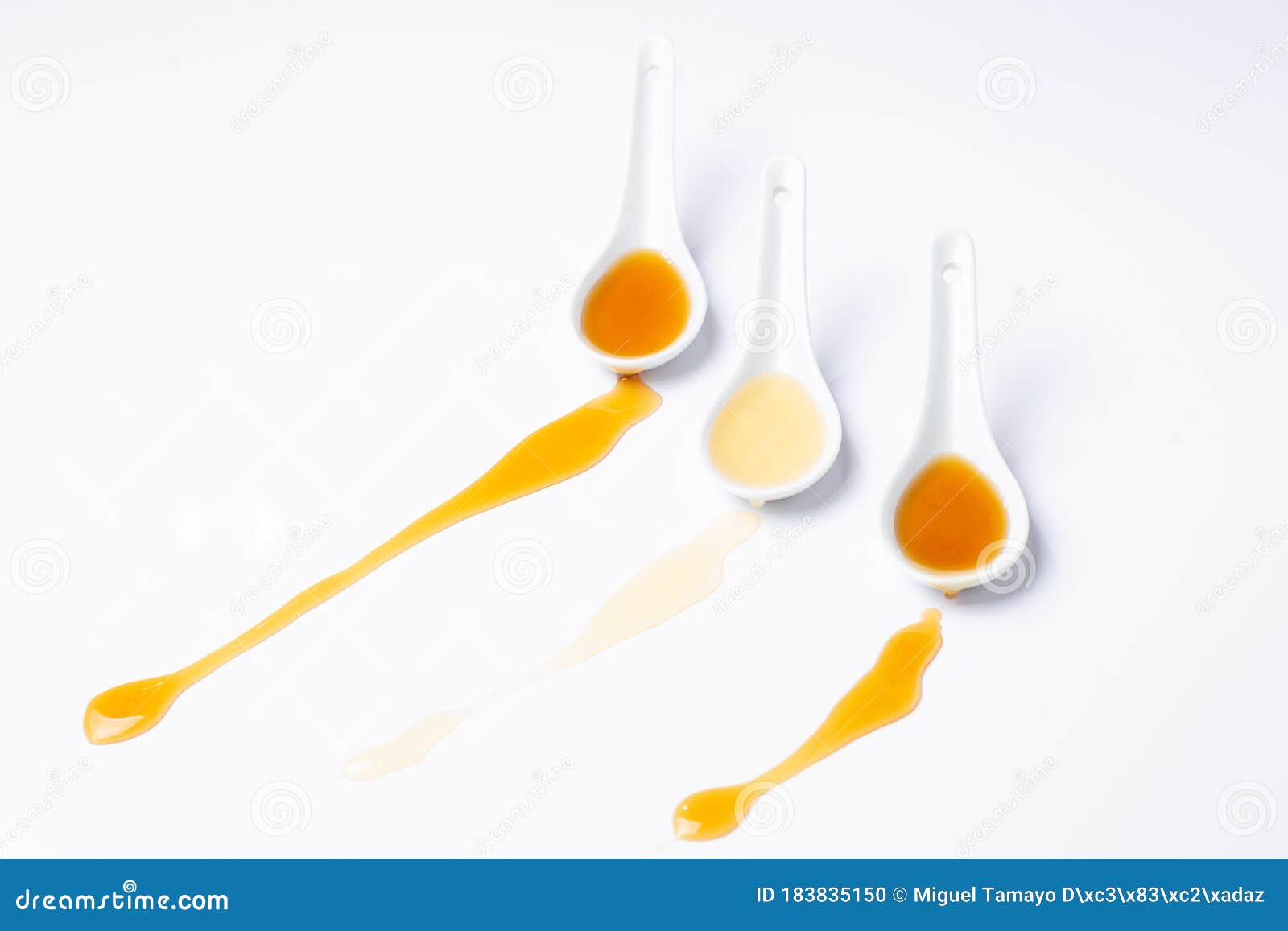 Three White Spoons With Spilled Honey Isolated On White Background