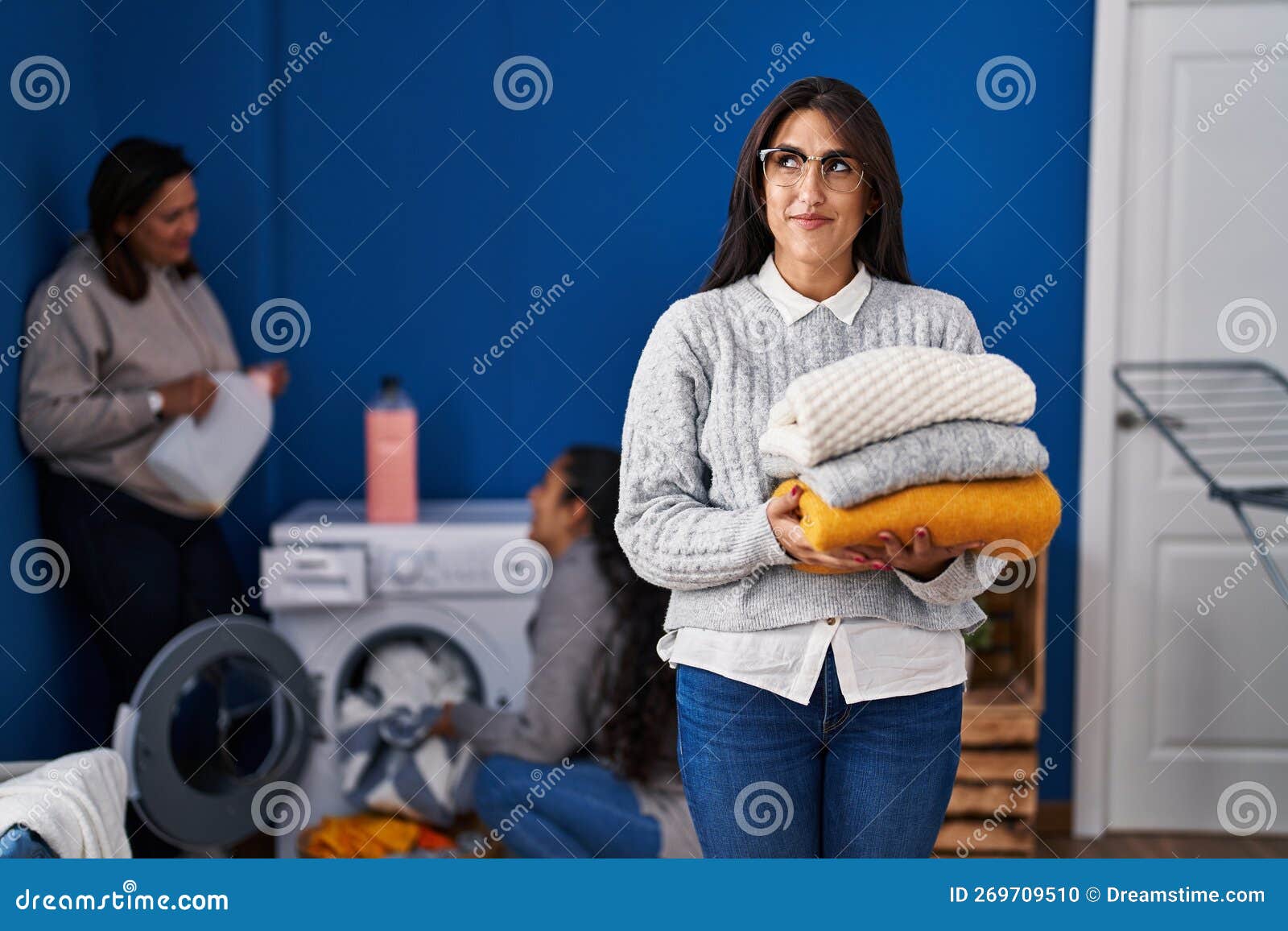 Three Women Doing Laundry at Home Smiling Looking To the Side and