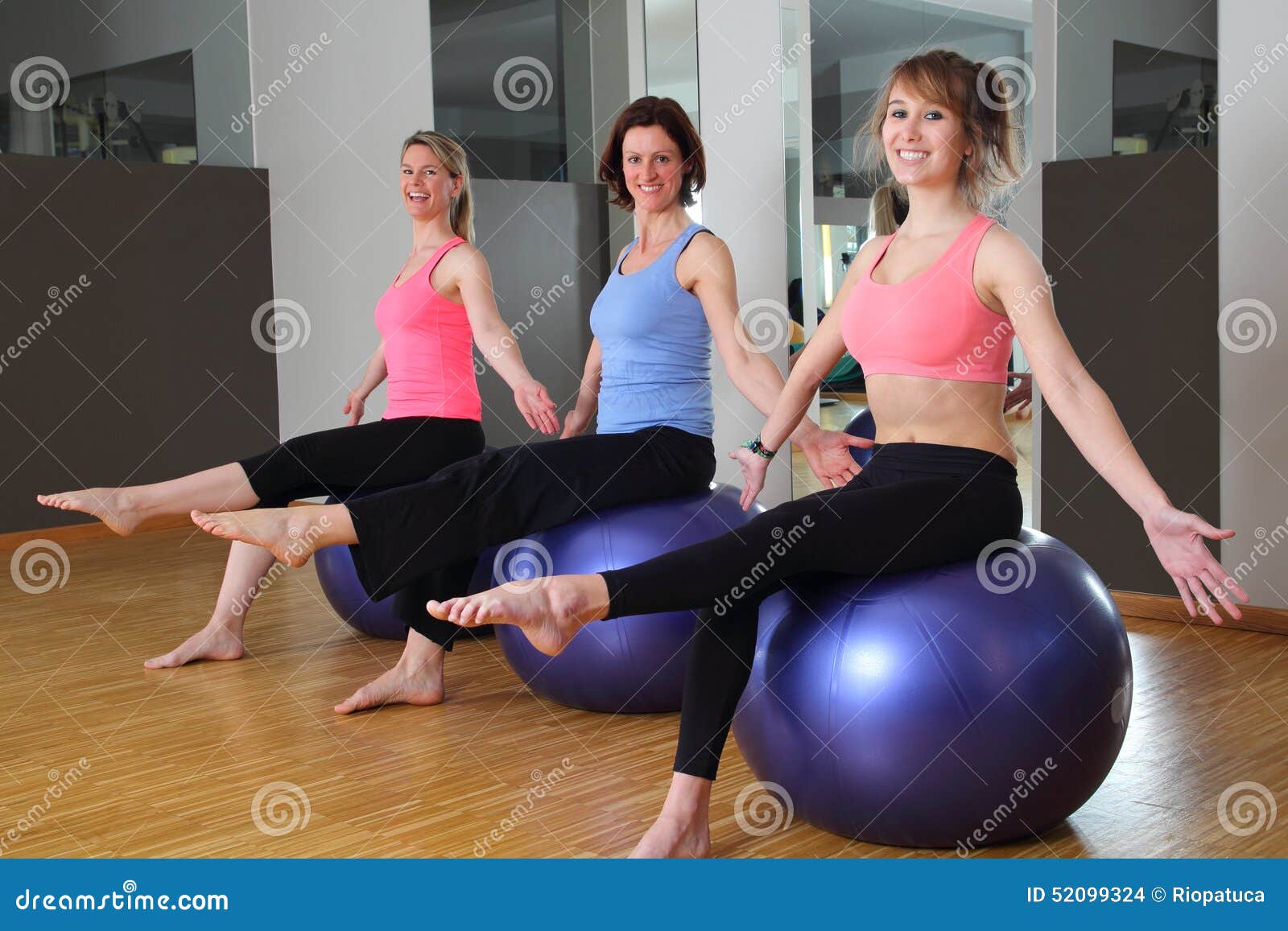 Three Women on Exercise Balls in a Gym Hands Legs Up Stock Photo