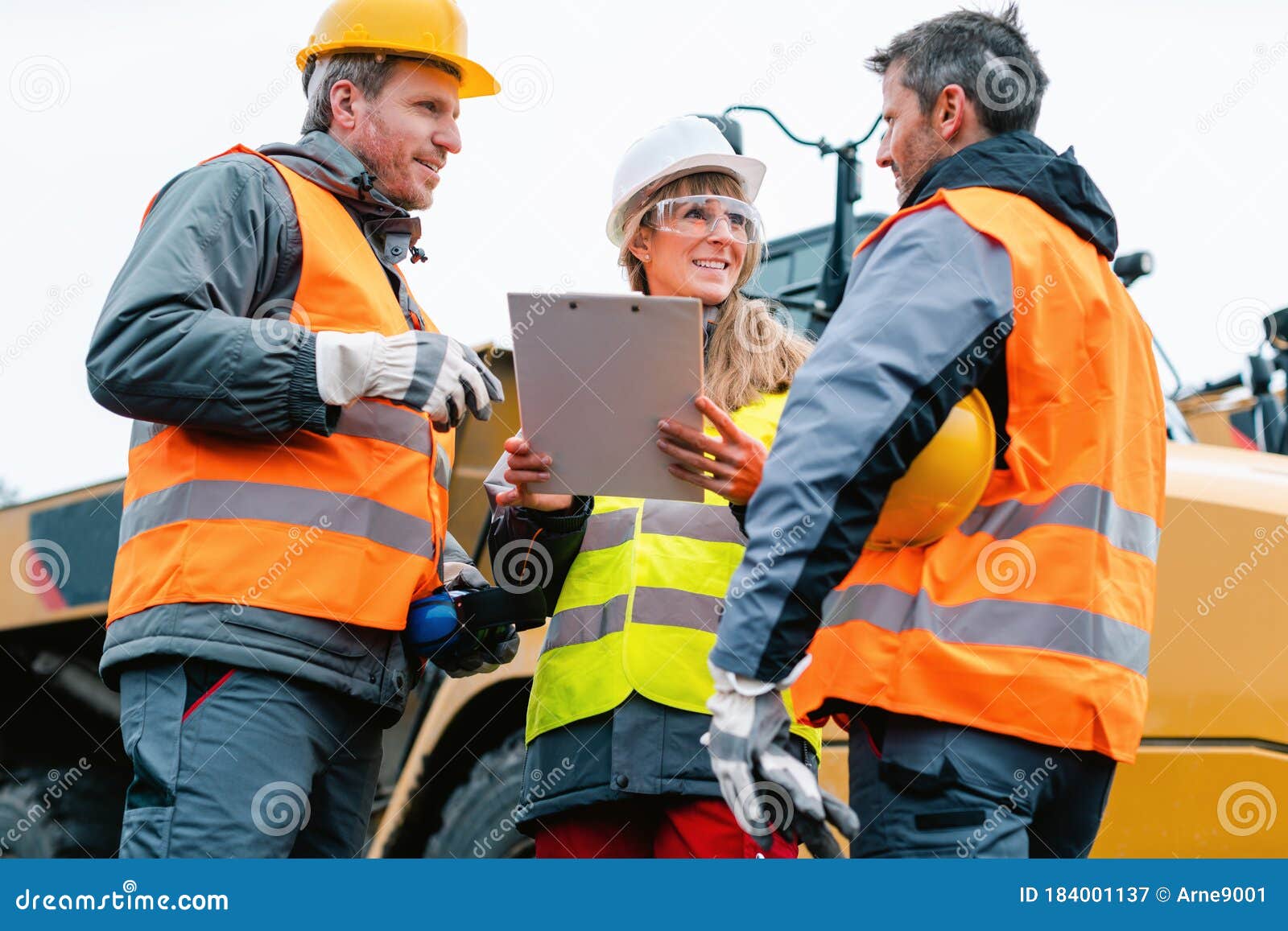 Three Workers in a Quarry Discussing in Front of Heavy Machinery Stock Image Image of industry