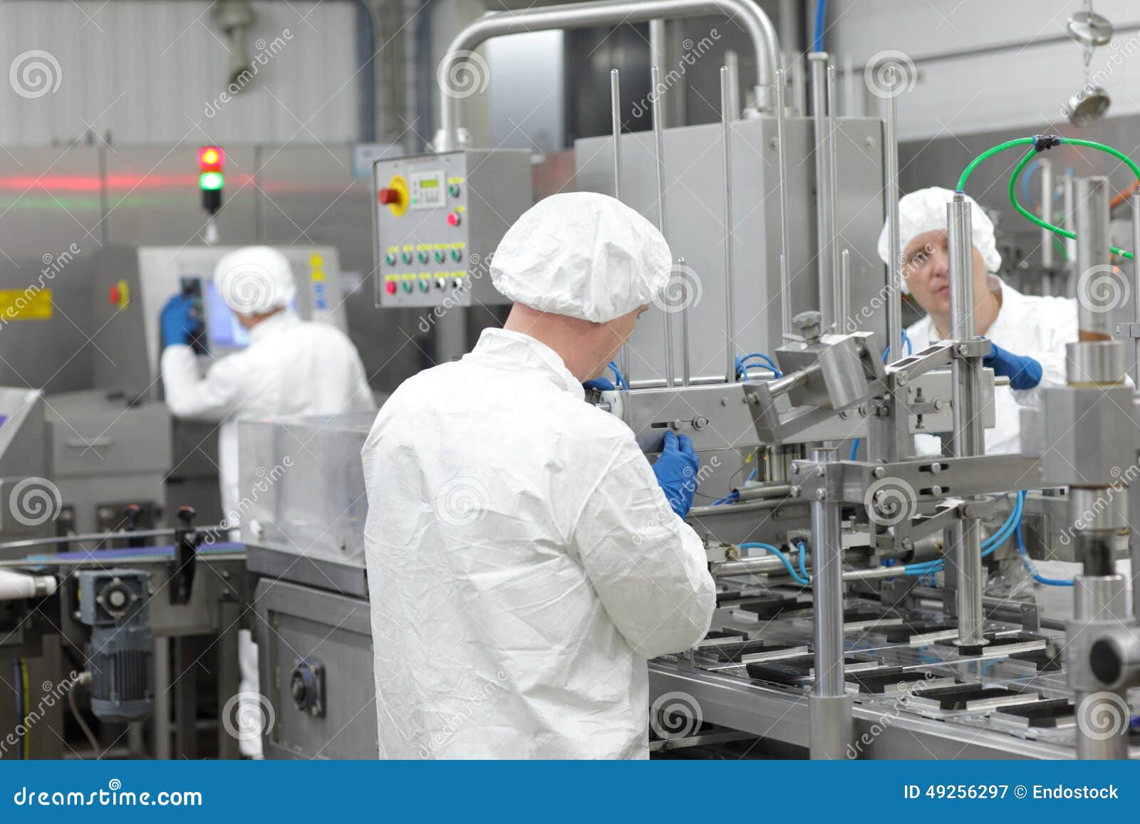 three workers in uniforms at production line in plant