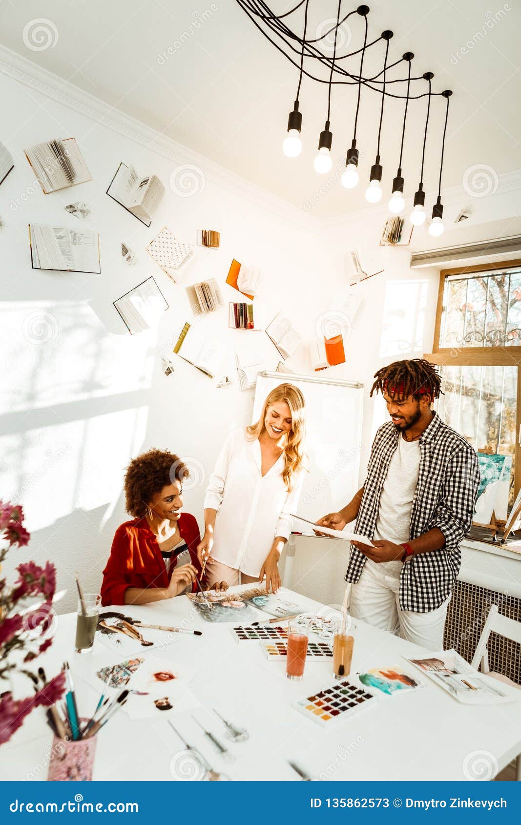 Three Young Artists Working in Light Decorated Studio Stock Image