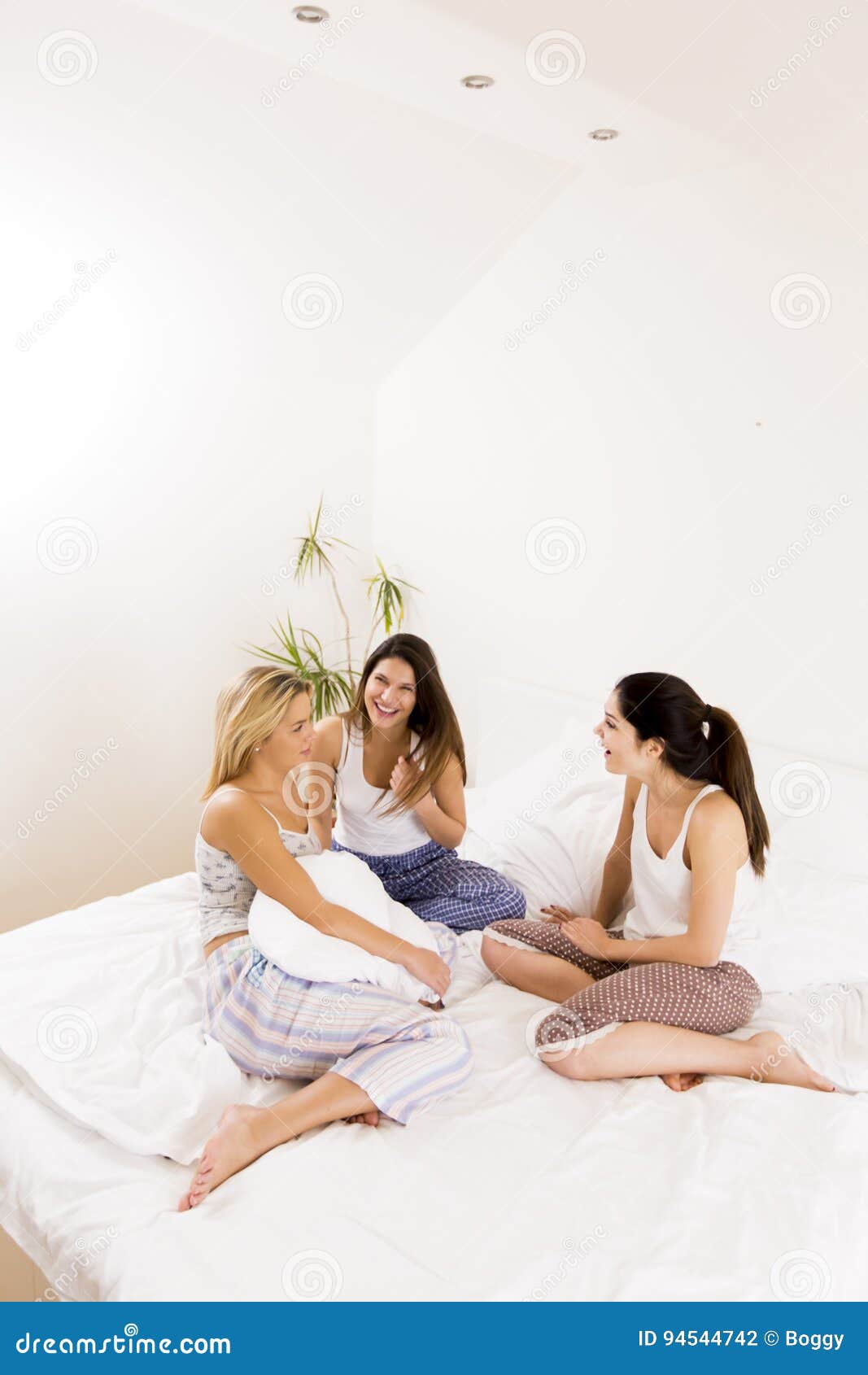Three Young Girls Sitting on the Bed in the Bedroom and Talk Stock