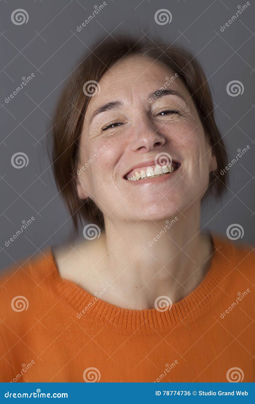 thrilled middle aged woman with brown hair laughing, blur effects