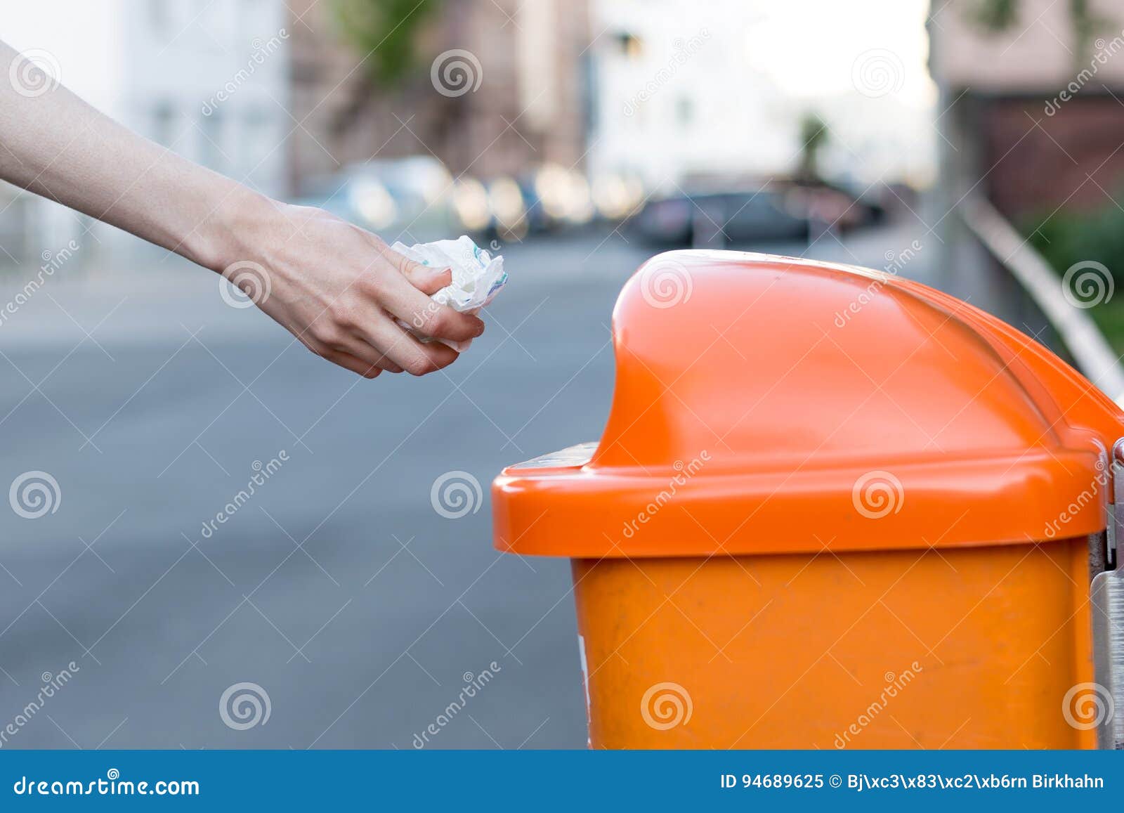 Throwing Waste into a an Orange Trash Can in the Street Stock Image