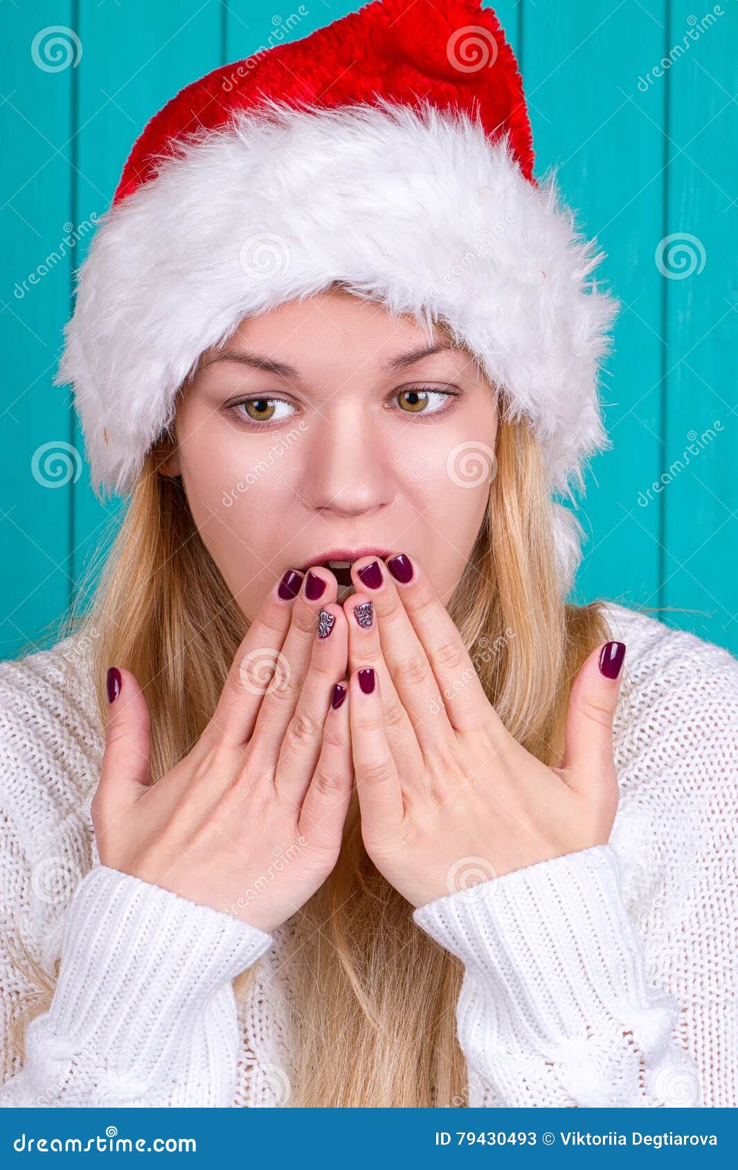 Tiempo de la Navidad Mujer joven que lleva el vestido rojo del sombrero de Papá Noel en fondo azul Expresión sorprendida de la cara