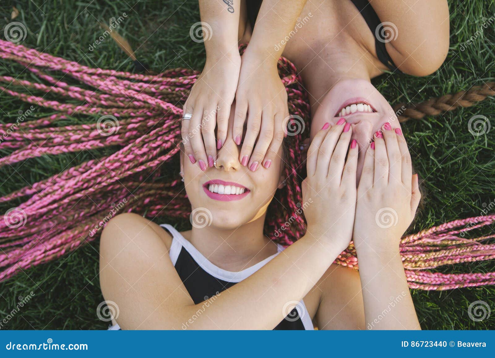 Tienervrienden in speelse houding. Tienervrienden in speelse die houding op het gras wordt geïsoleerd